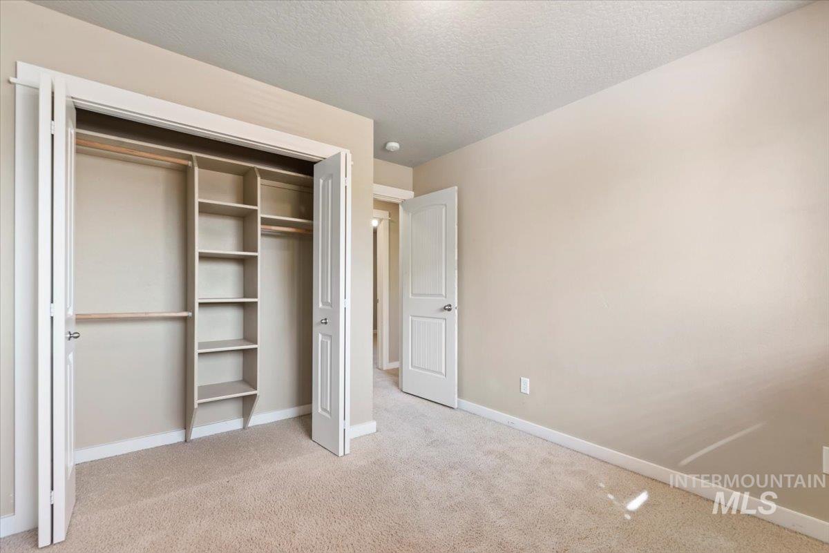 Unfurnished bedroom featuring a textured ceiling, light colored carpet, and a closet