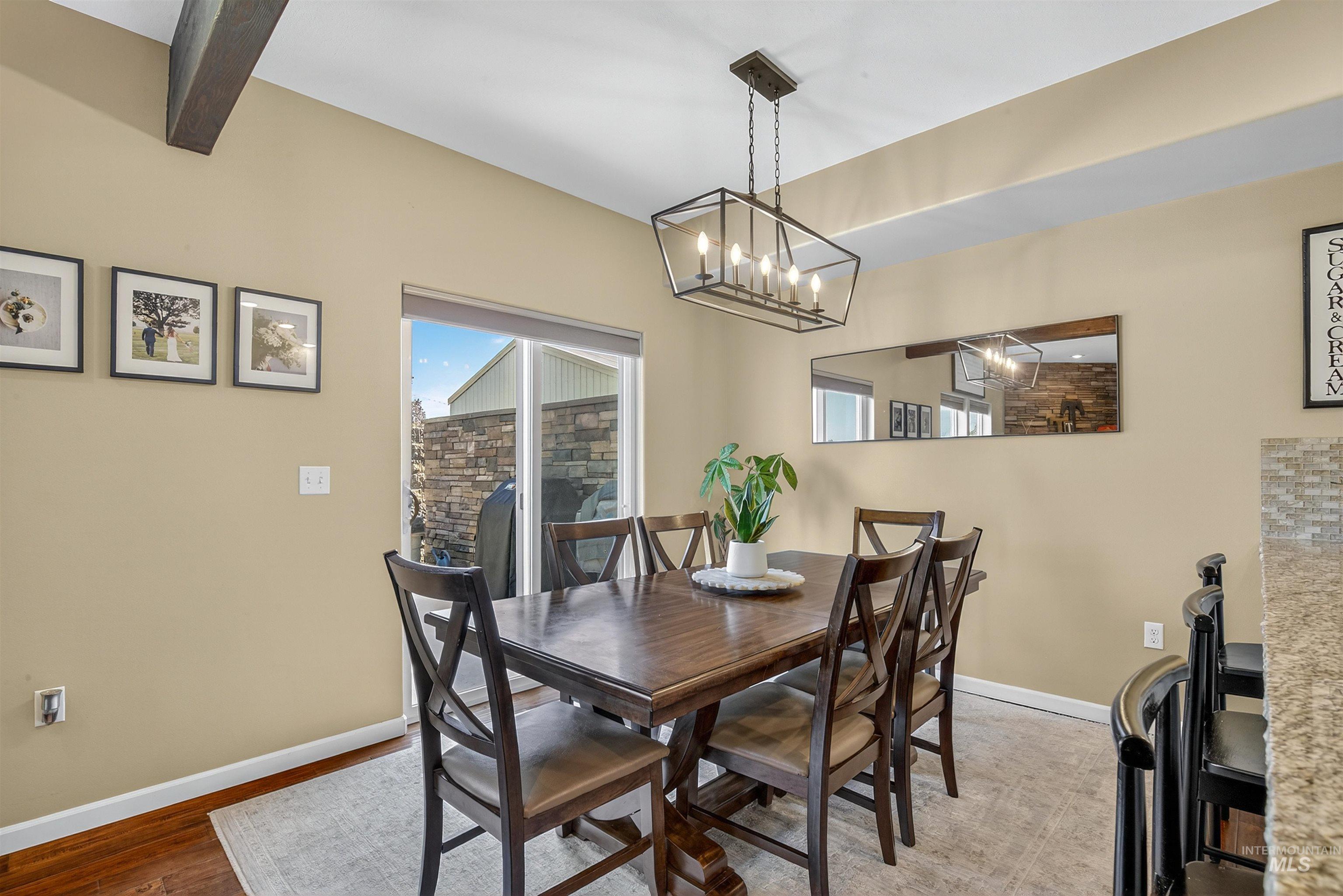 Dining space with wood finished floors and beam ceiling