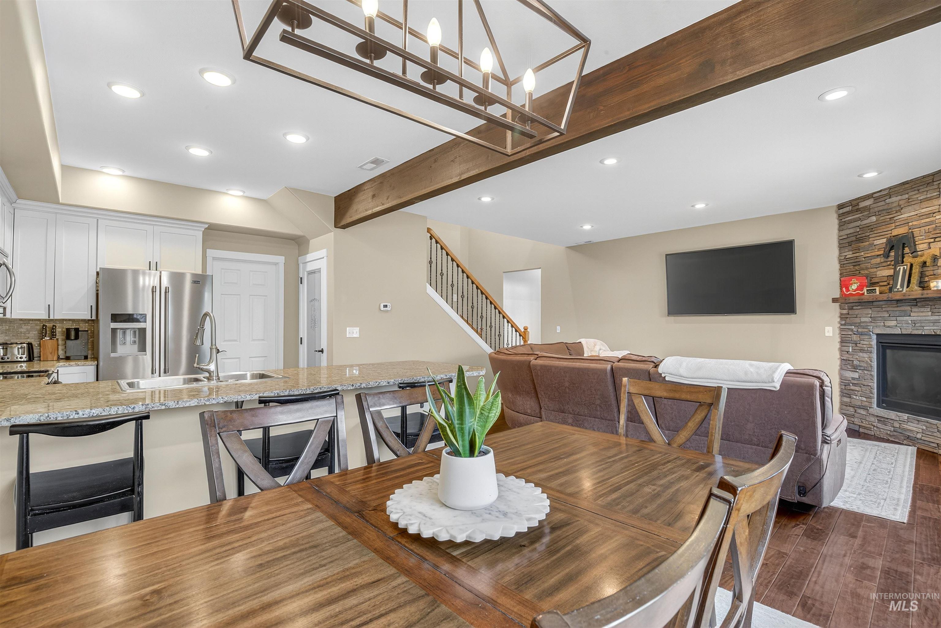 Dining room featuring beamed ceiling, recessed lighting, stairway, a stone fireplace, and wood finished floors