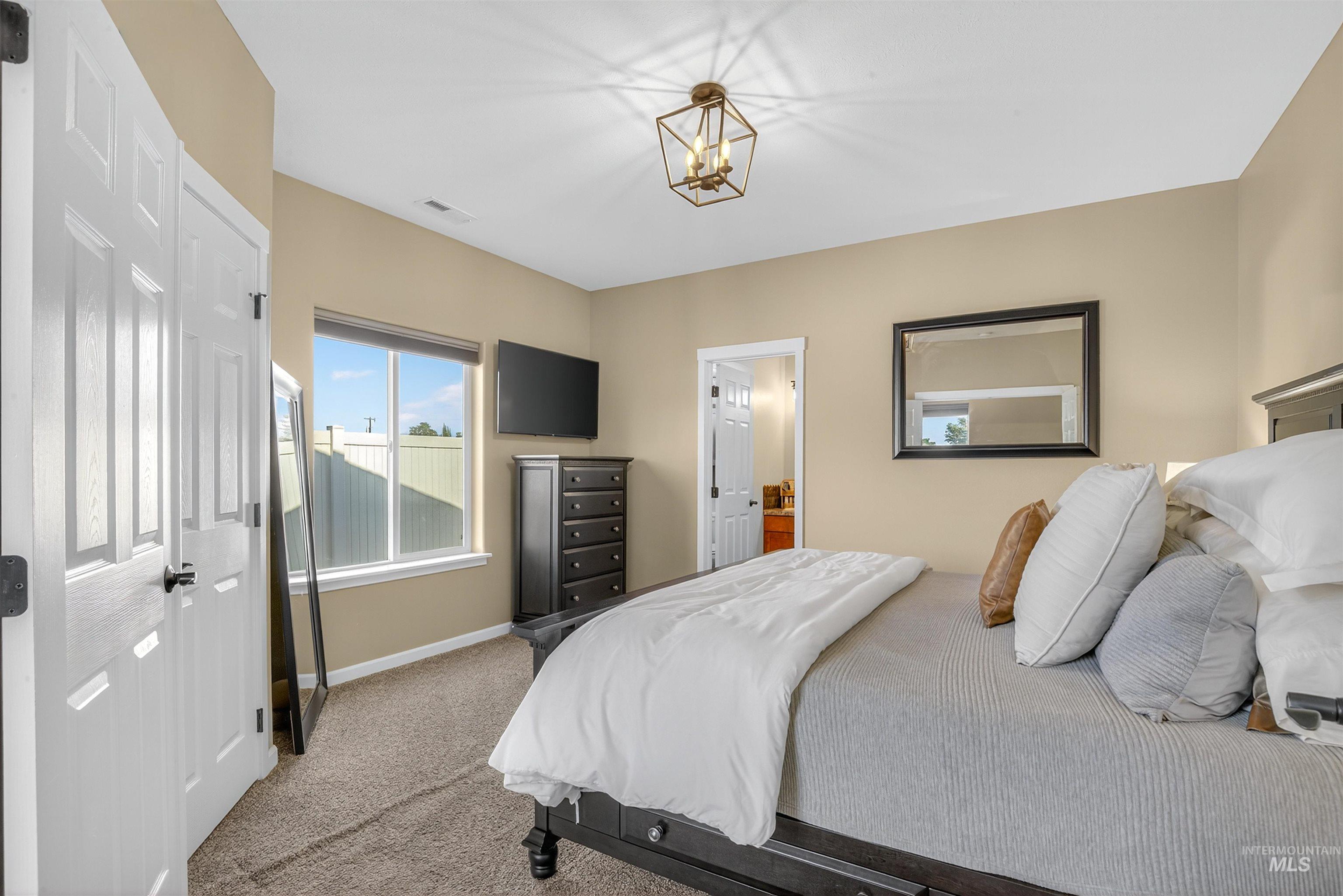 Bedroom with carpet flooring, connected bathroom, and a chandelier