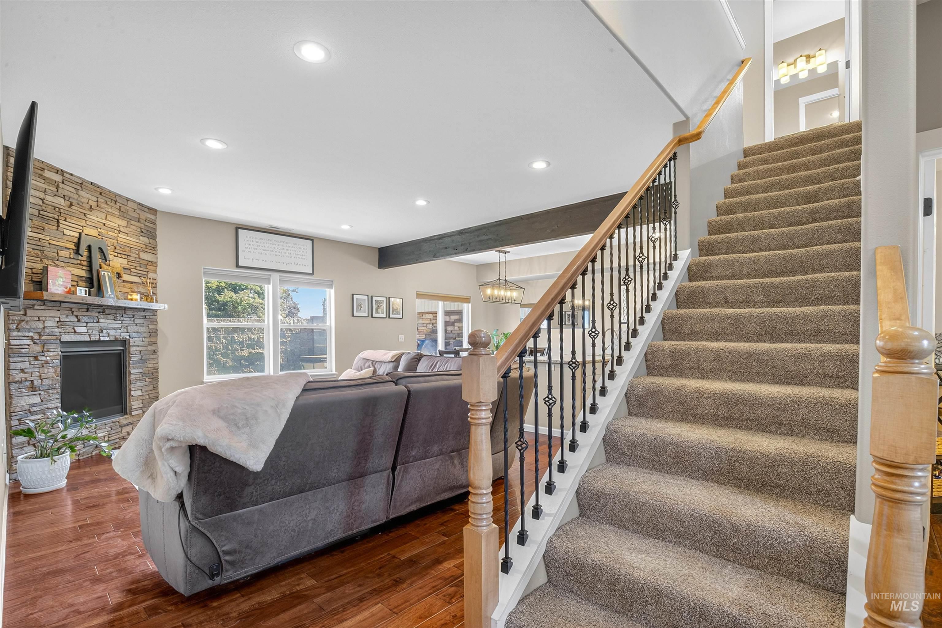 Living room with stairs, wood finished floors, a chandelier, recessed lighting, and a fireplace