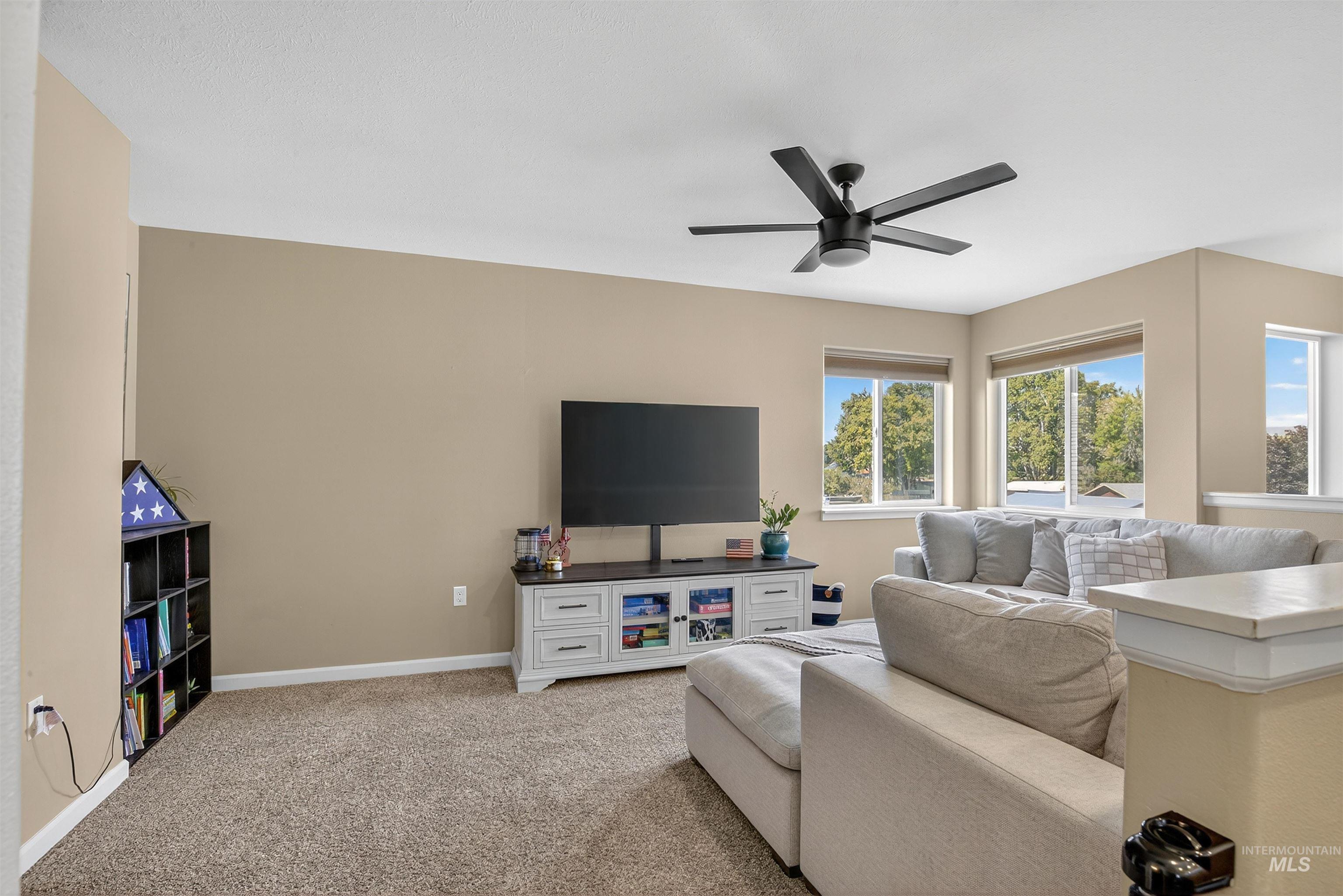 Living room featuring light carpet and a ceiling fan