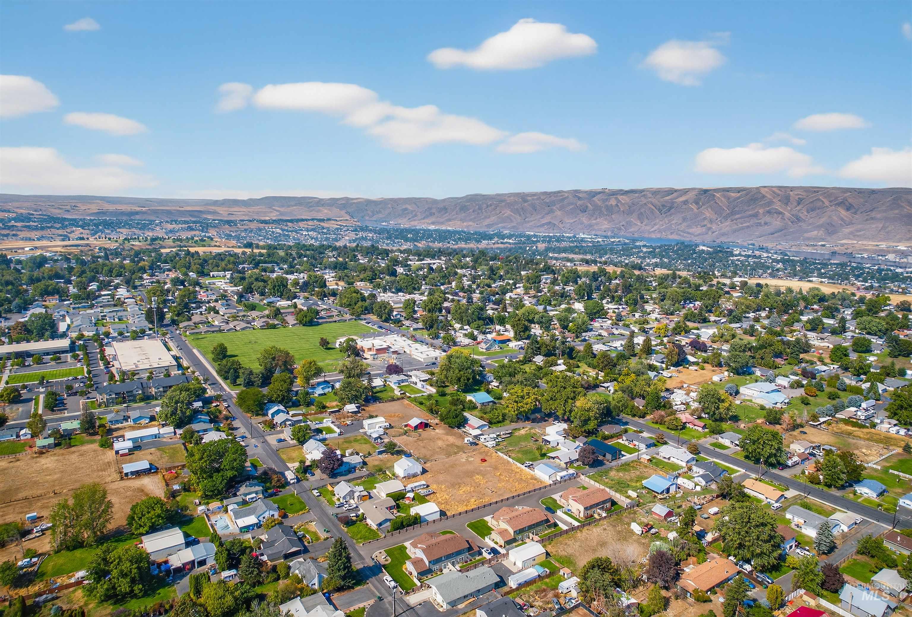 Aerial view of property and surrounding area with a mountain backdrop and nearby suburban area