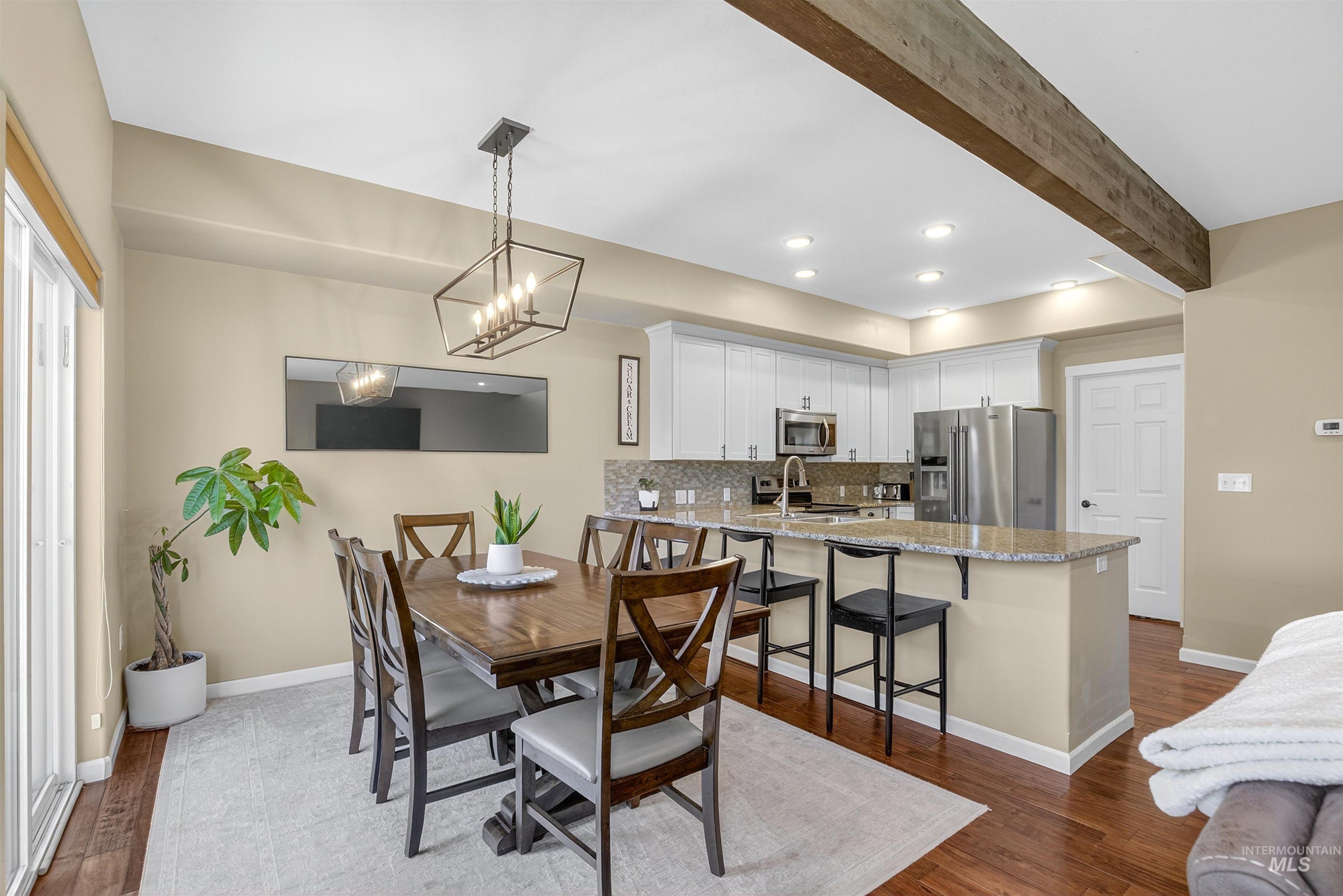 Dining space with beamed ceiling, dark wood-type flooring, recessed lighting, and a chandelier