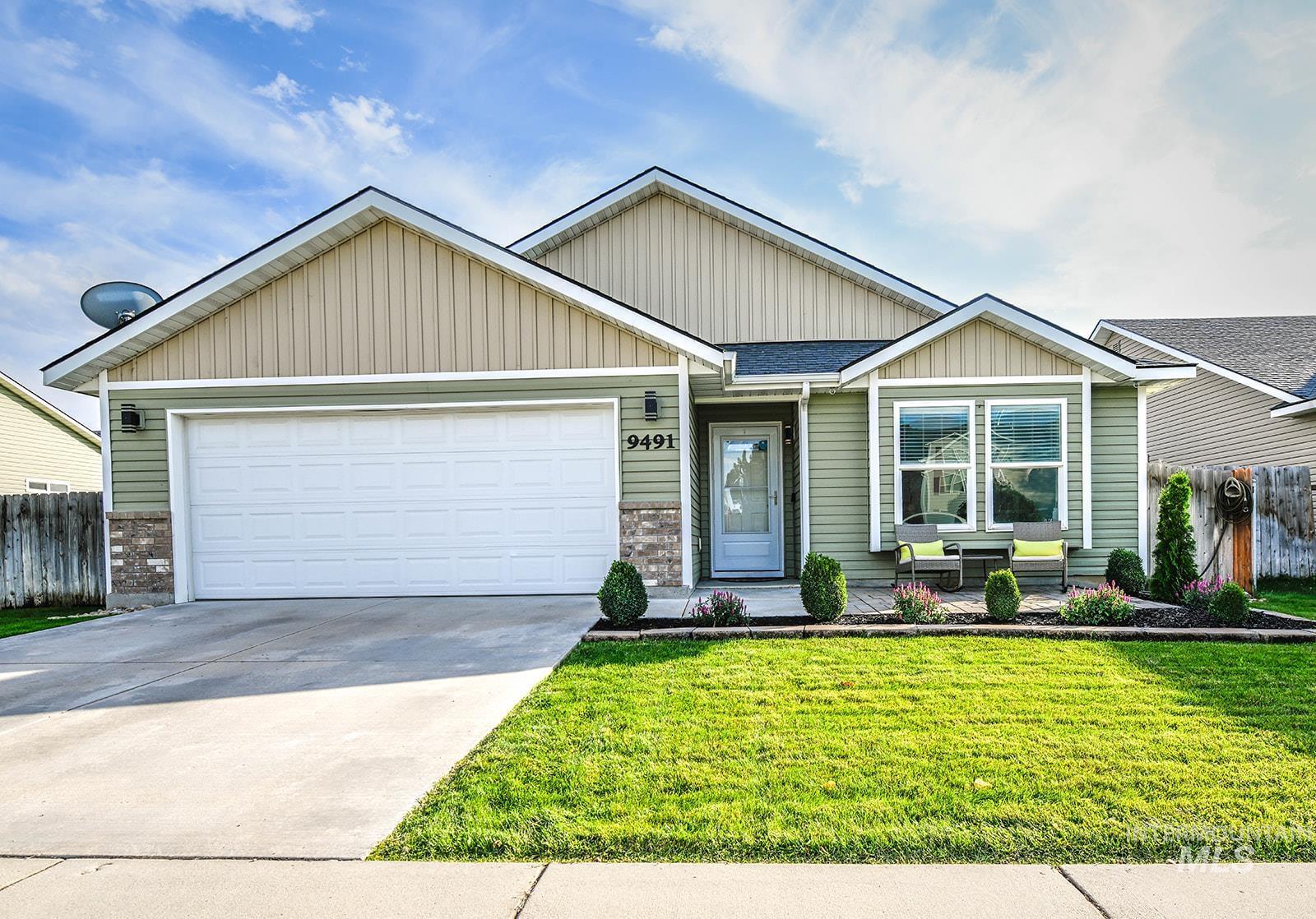 View of front facade with board and batten siding, concrete driveway, an attached garage, and brick siding