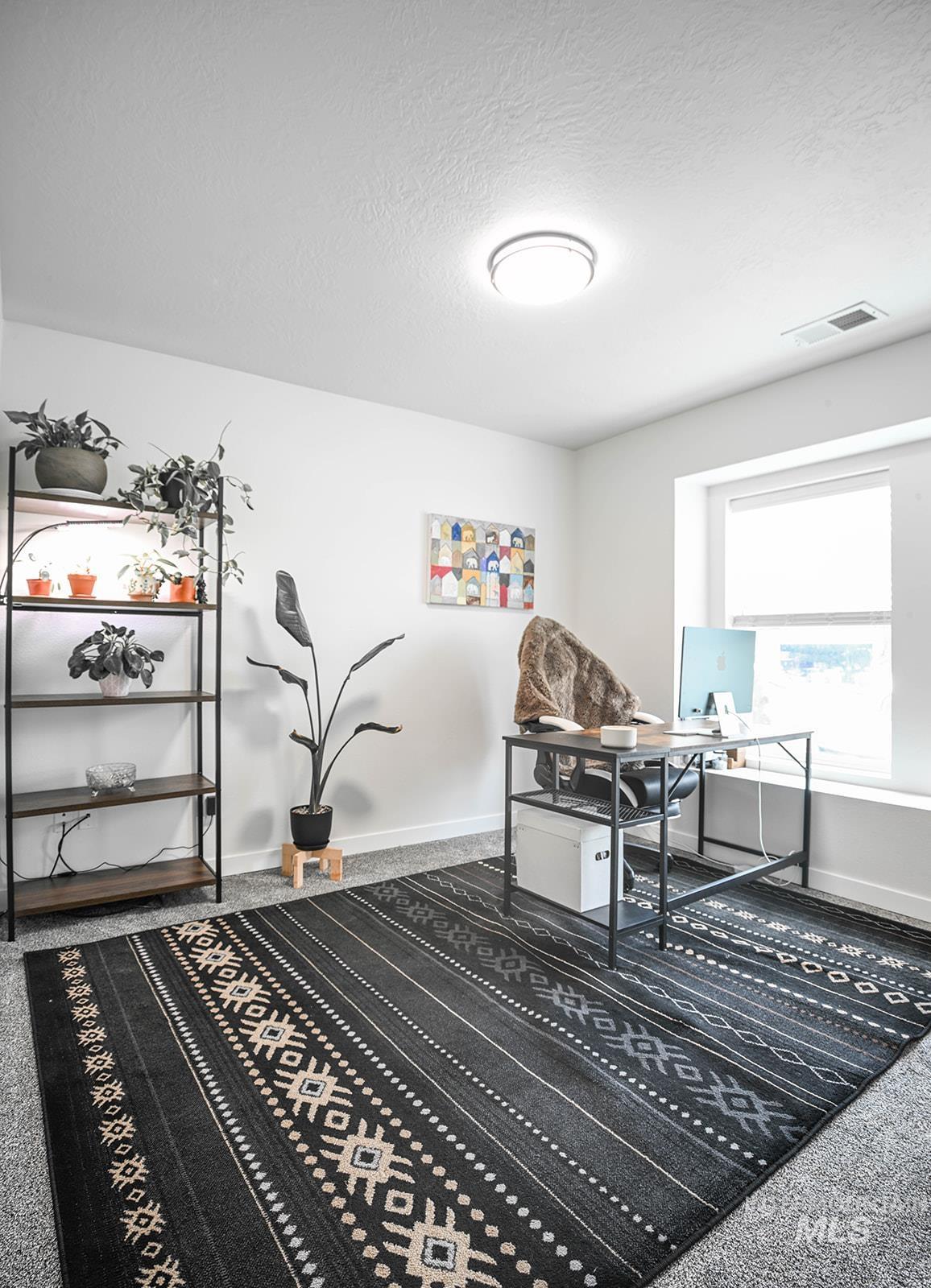Home office featuring carpet floors and a textured ceiling