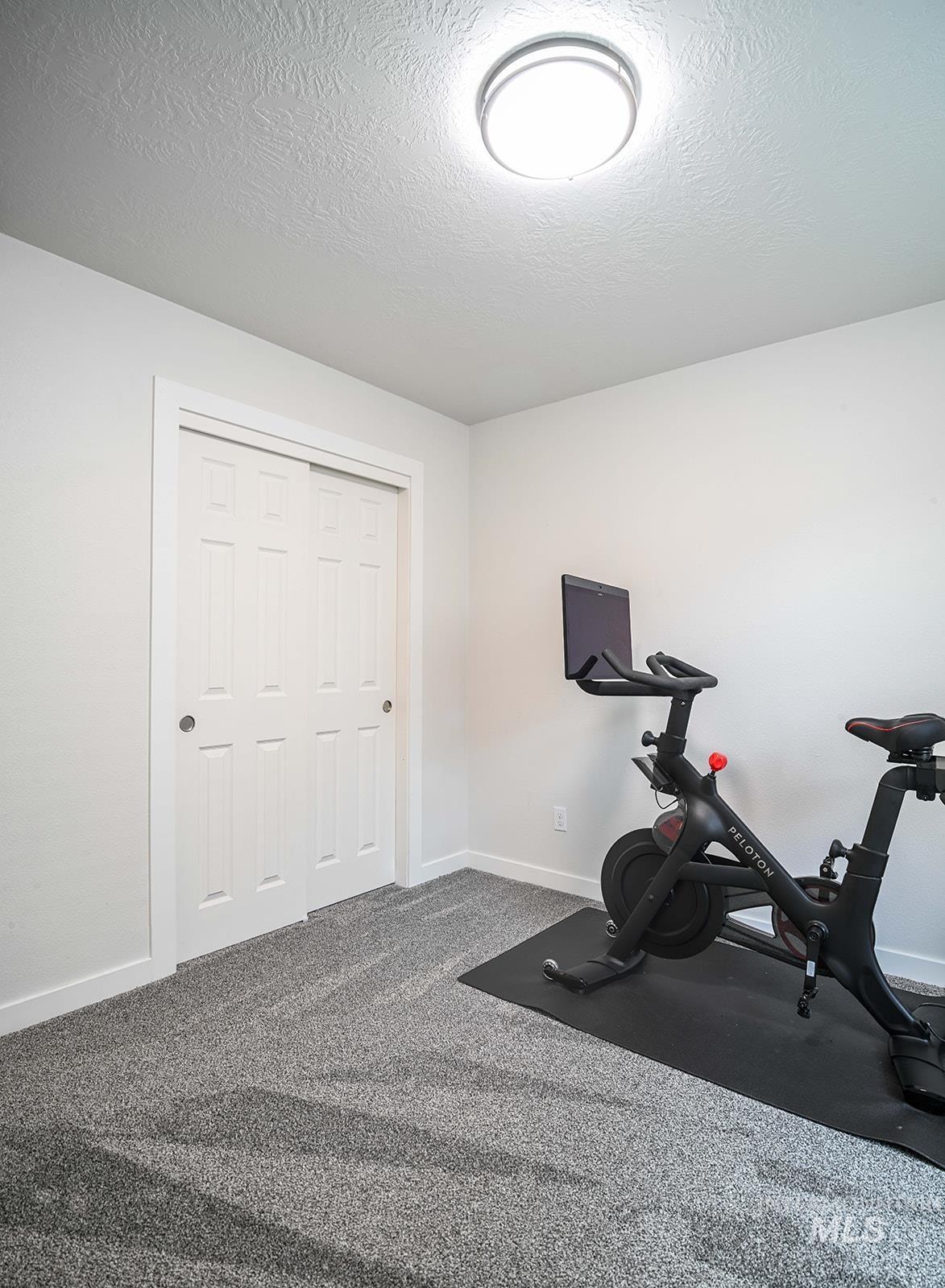 Exercise room with a textured ceiling and carpet floors