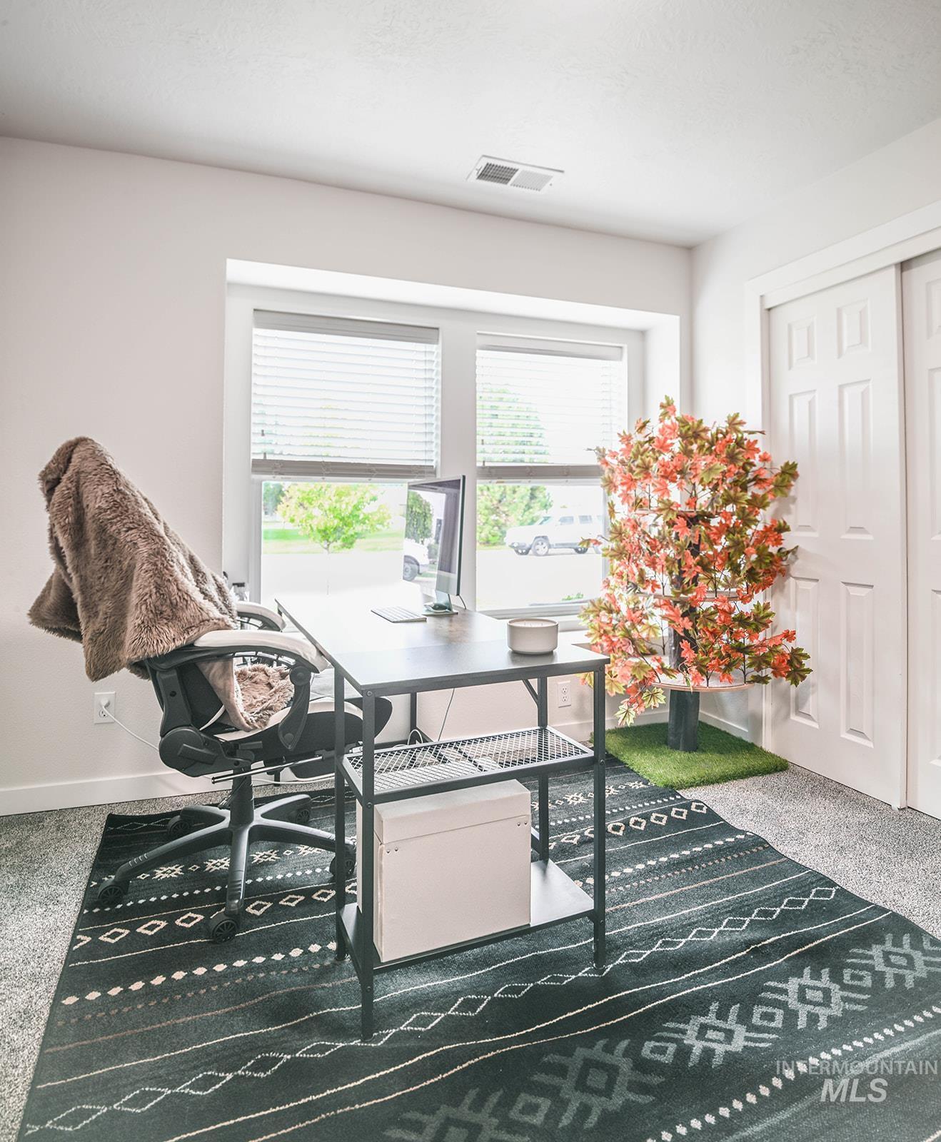 Carpeted office space with baseboards and a desk