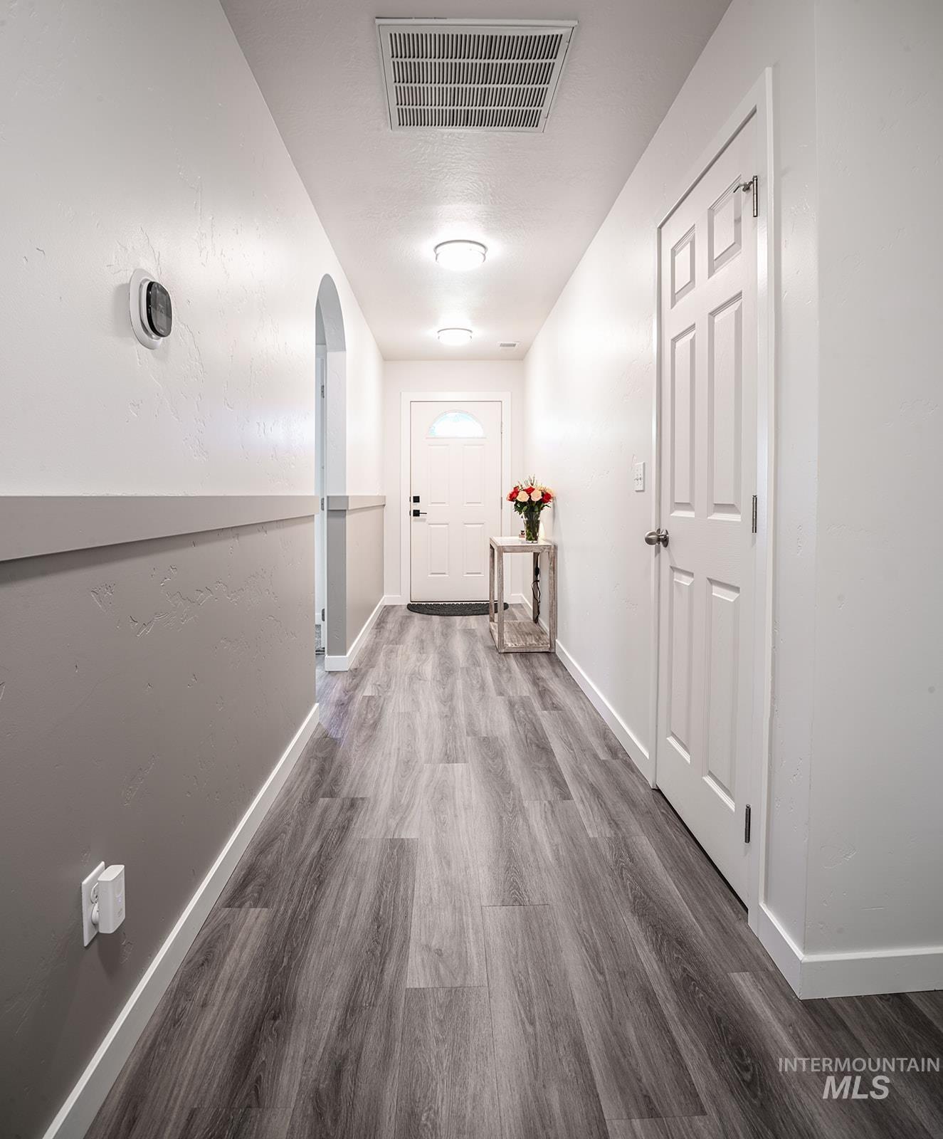 Corridor with arched walkways and dark wood-style floors