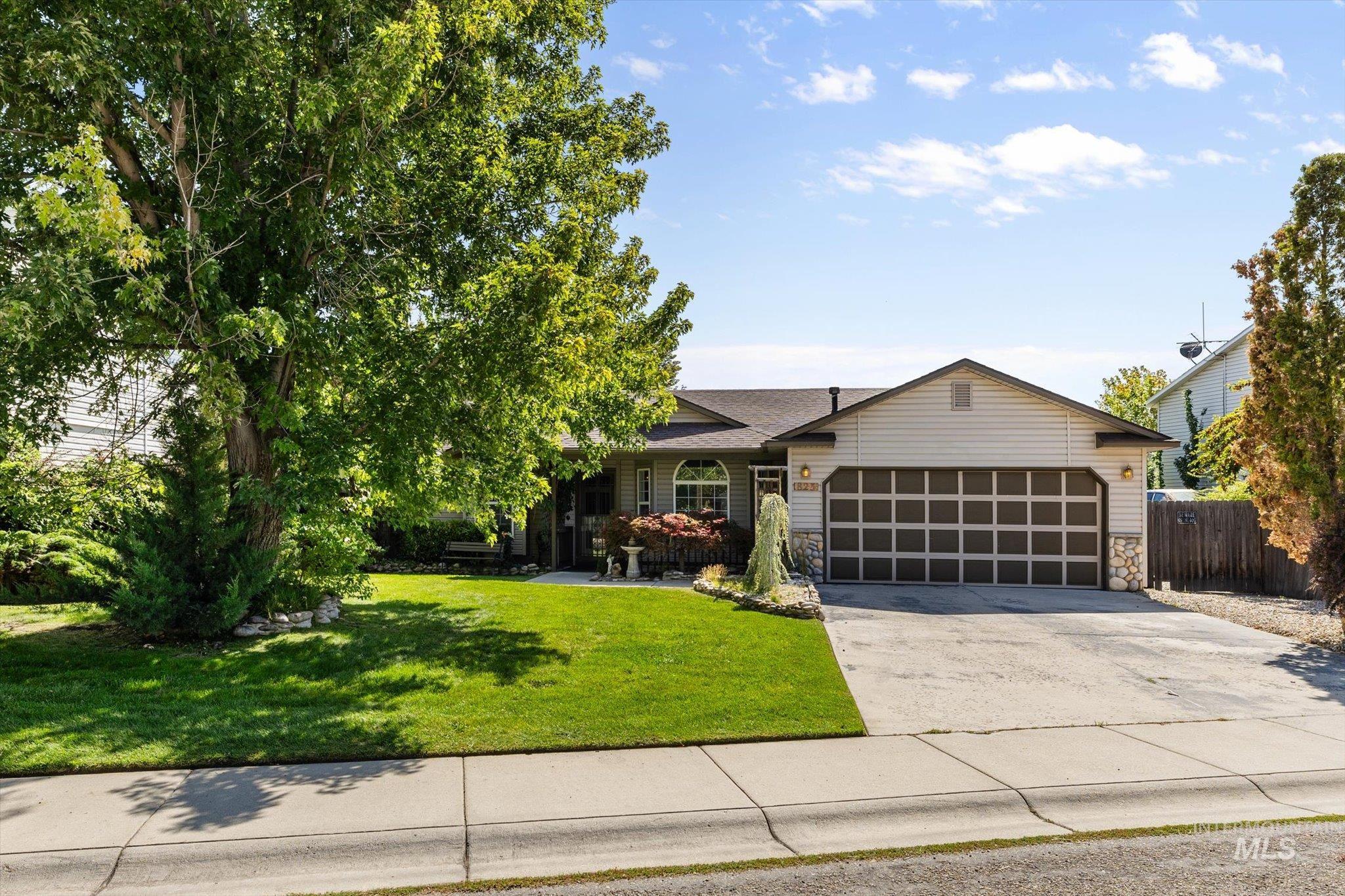 View of front of property featuring driveway, stone siding, and an attached garage
