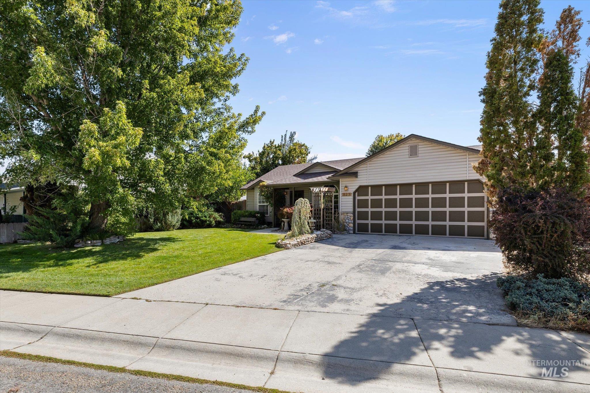 Ranch-style house featuring a front yard, concrete driveway, and an attached garage