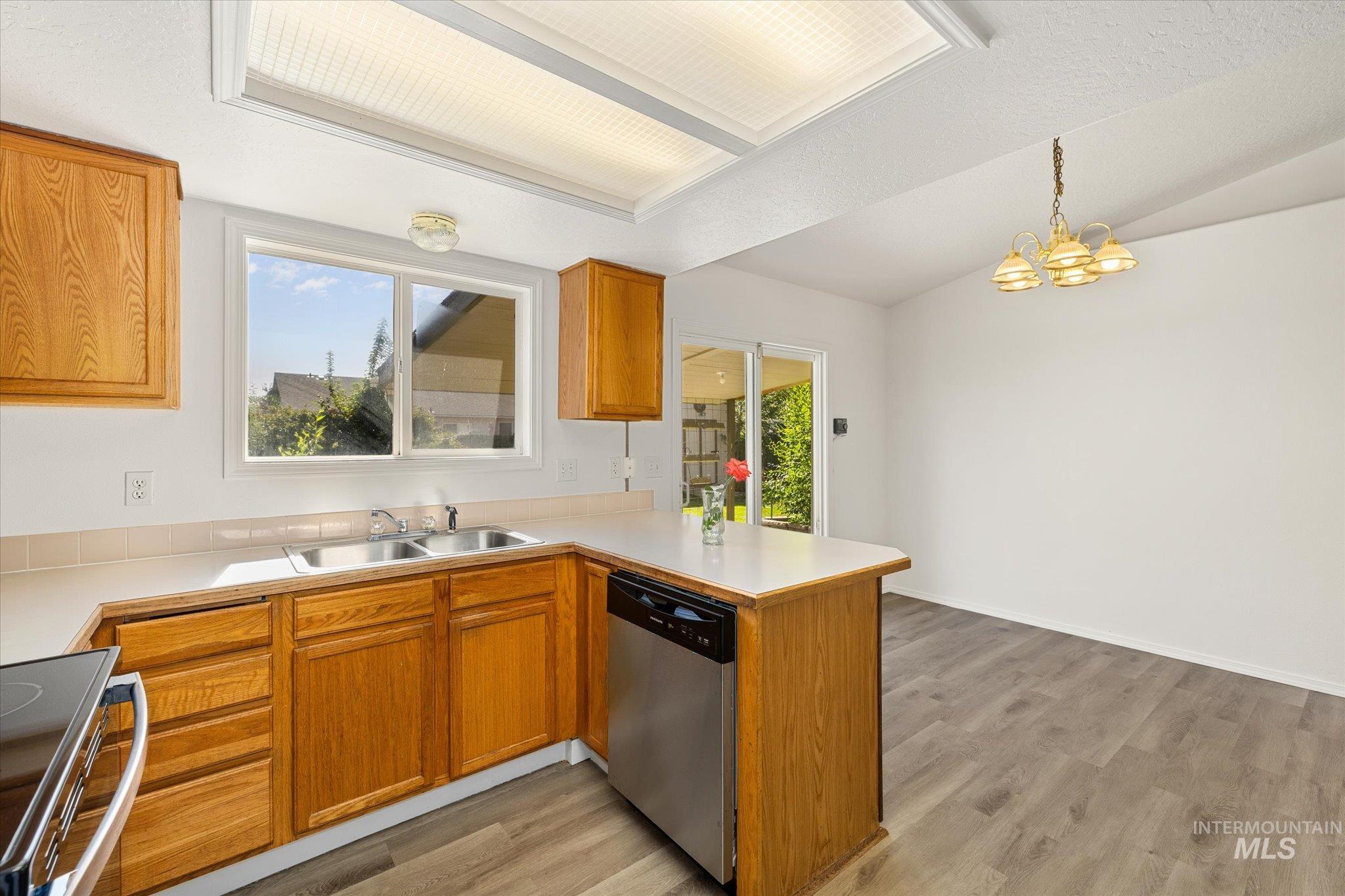 Kitchen with light countertops, brown cabinetry, range with electric cooktop, healthy amount of natural light, and lofted ceiling