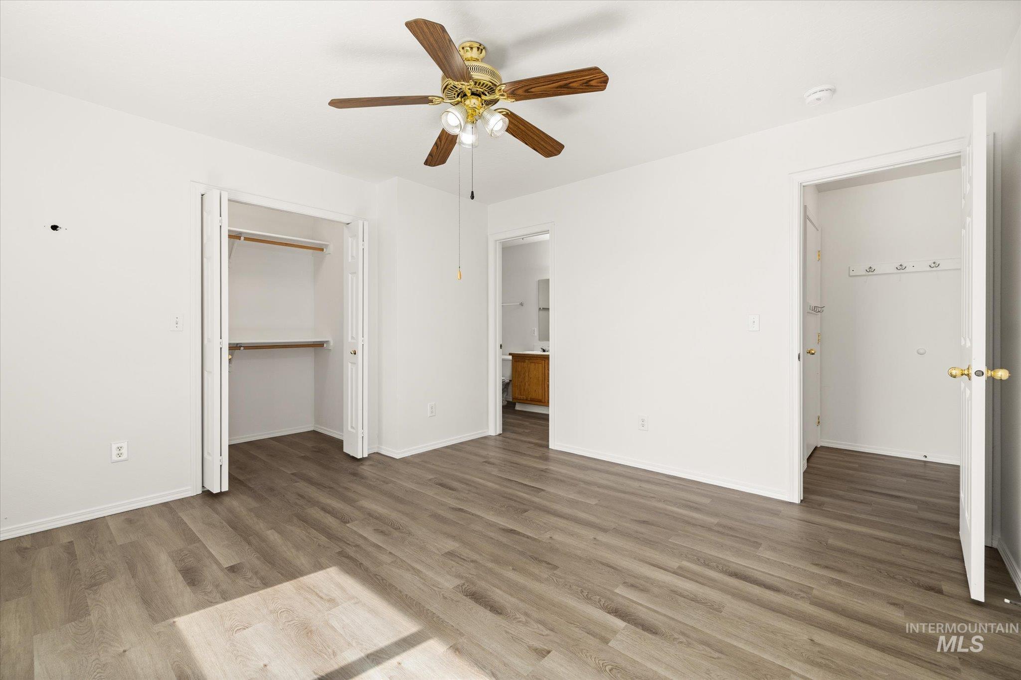 Unfurnished bedroom featuring light wood-style flooring, a closet, ceiling fan, and ensuite bath
