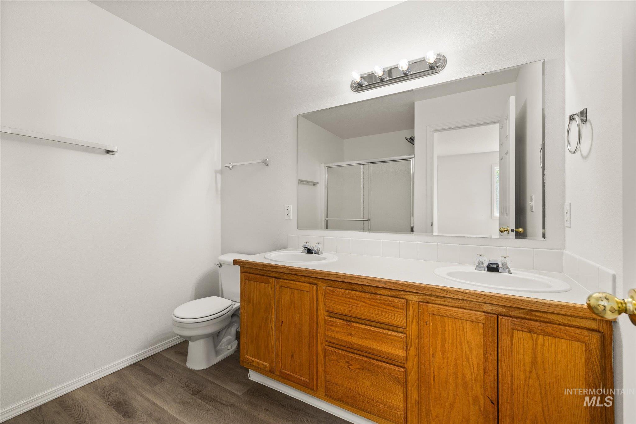 Bathroom featuring a shower stall, dark wood-type flooring, and double vanity