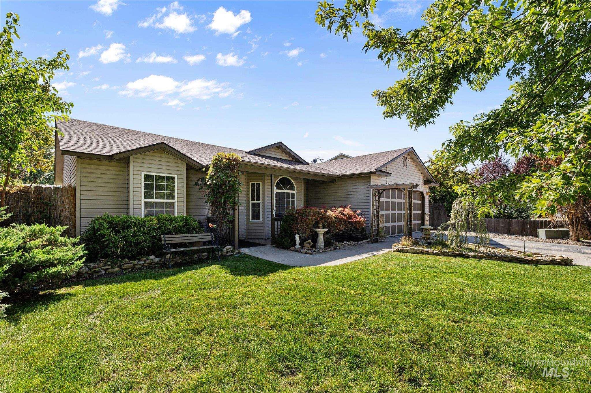 Ranch-style home featuring a shingled roof, a garage, and driveway