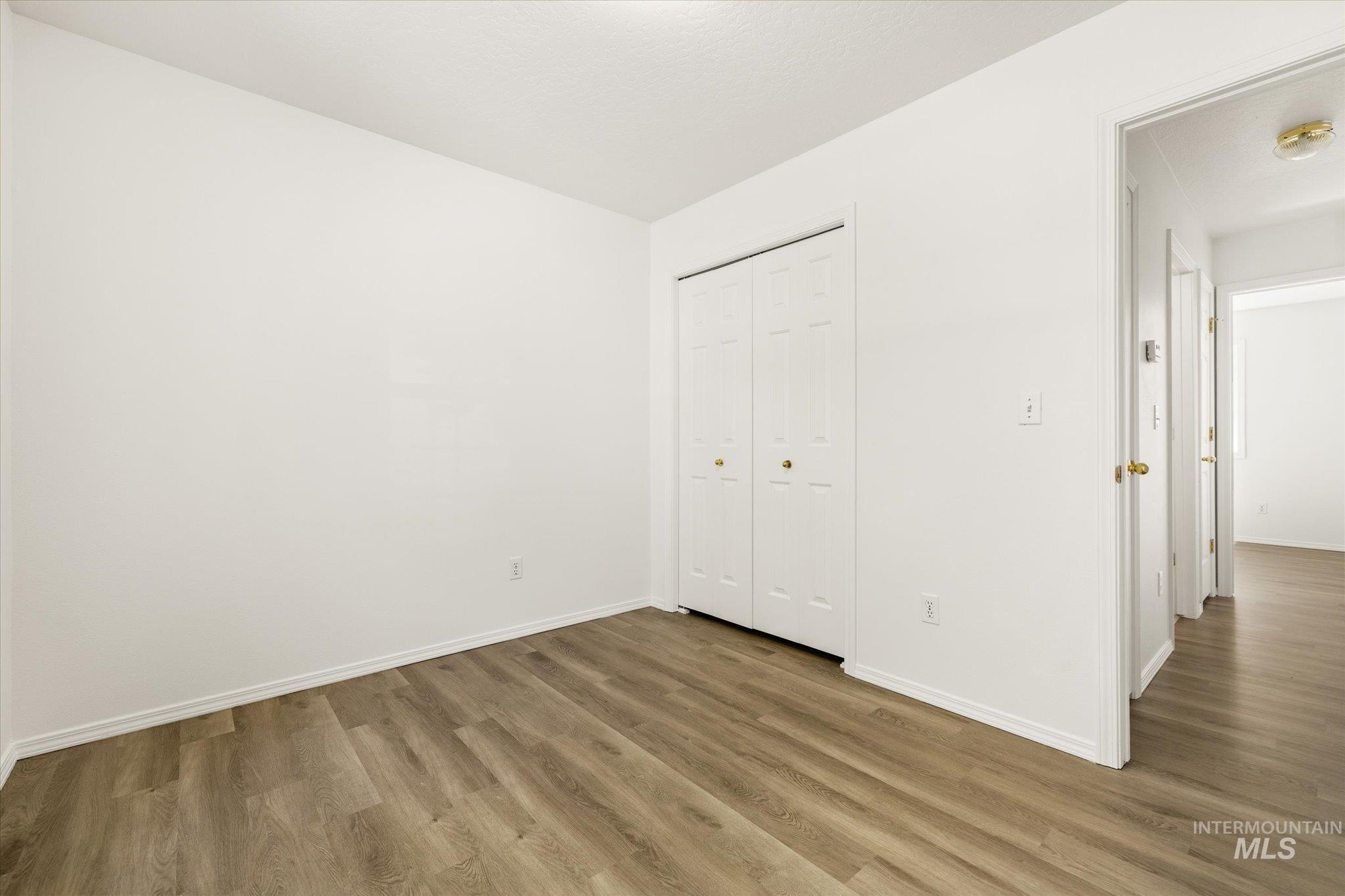 Unfurnished bedroom with wood finished floors and a closet