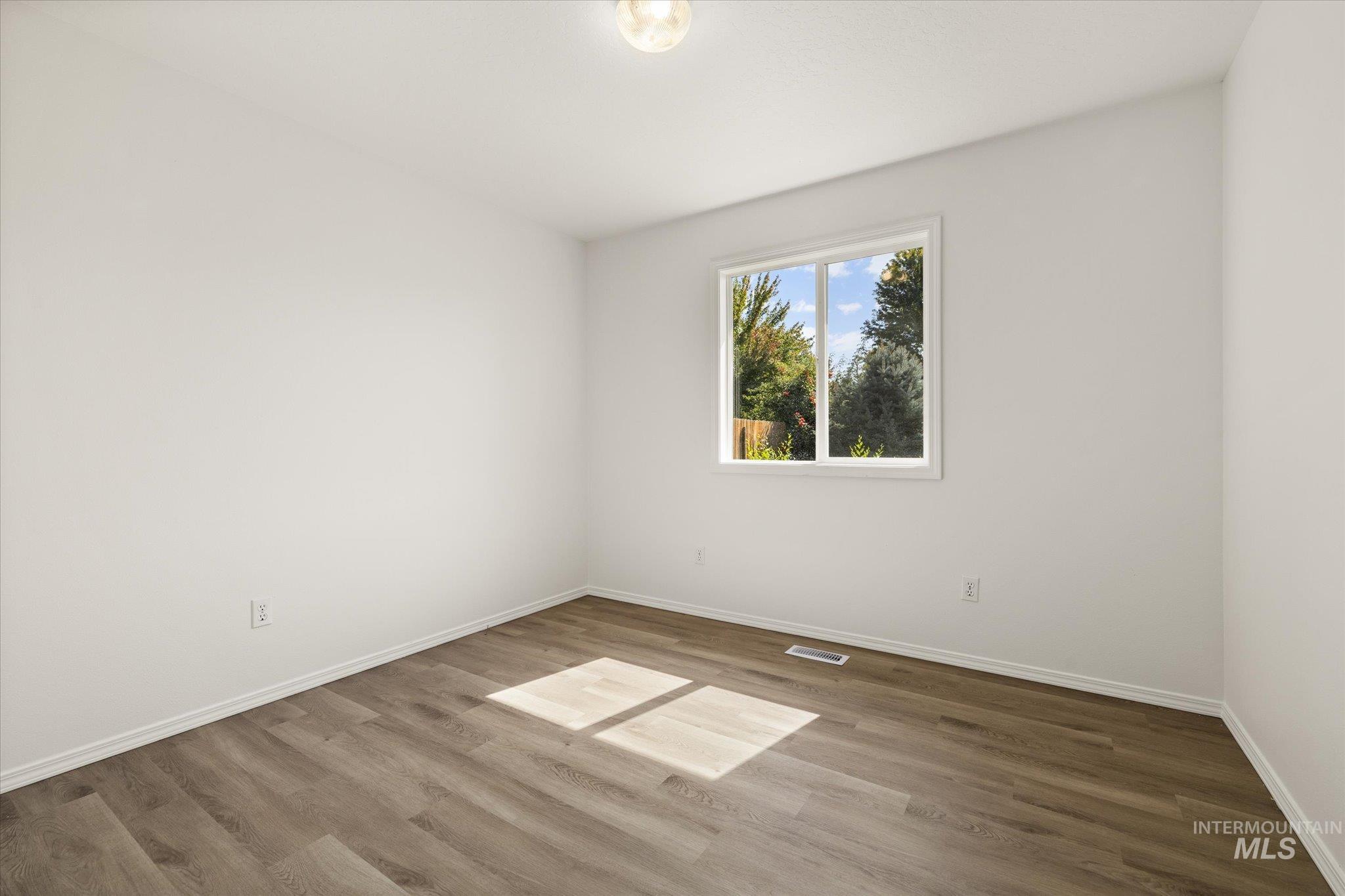 Spare room with baseboards and wood finished floors