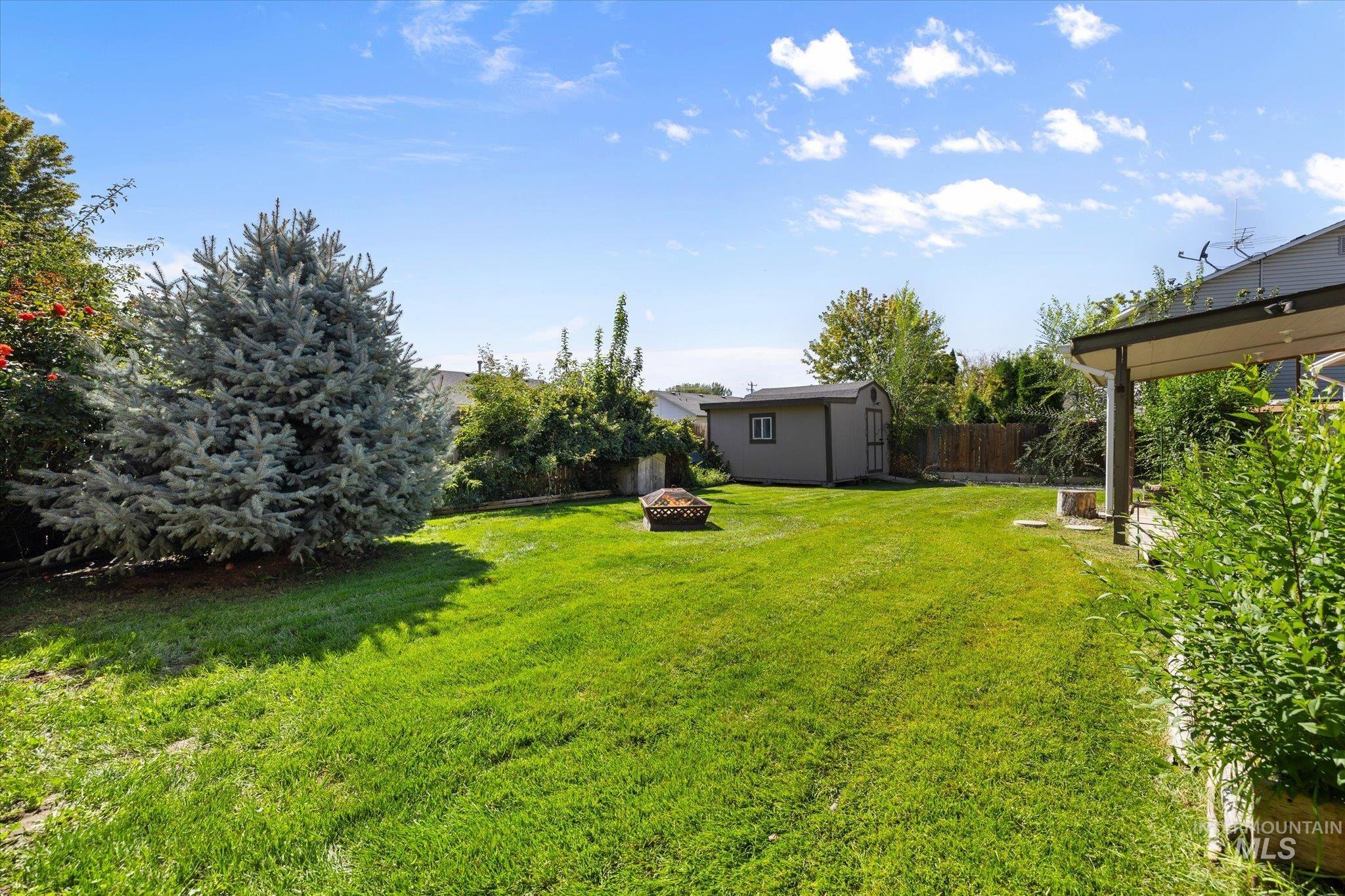 Fenced backyard with an outdoor fire pit and a storage shed