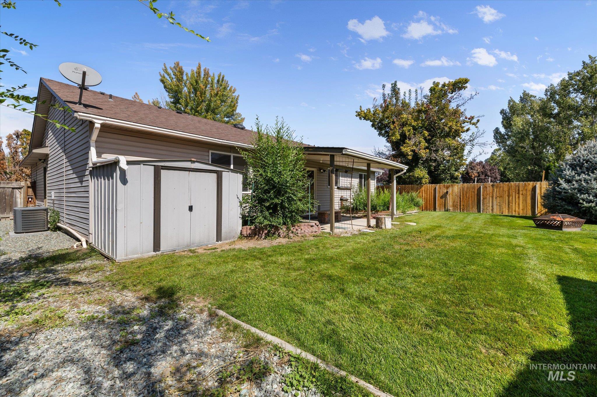 Back of property featuring a storage shed, a patio area, and an outdoor fire pit