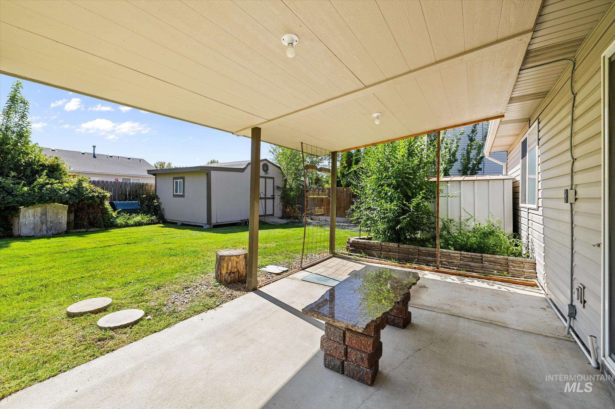 Fenced backyard featuring a shed and a patio
