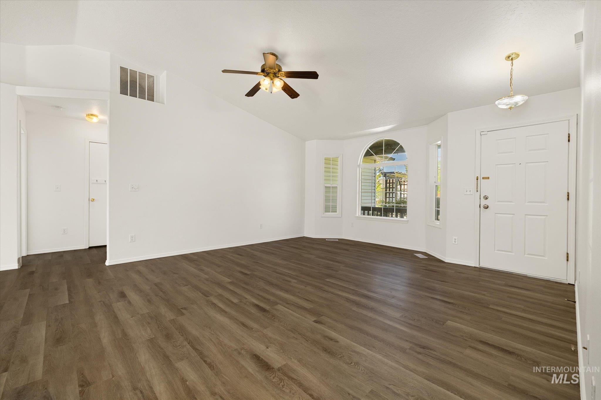Unfurnished living room featuring dark wood-style floors, a ceiling fan, and high vaulted ceiling