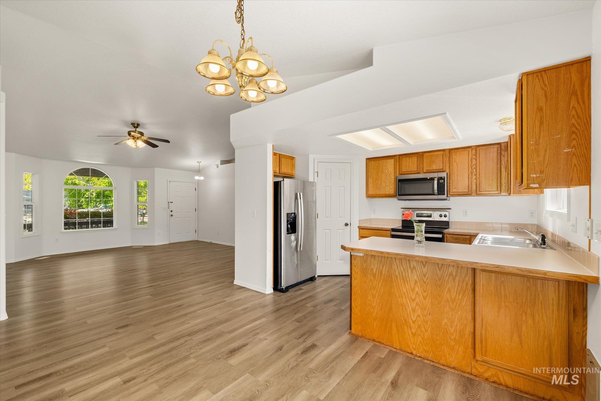 Kitchen with a peninsula, plenty of natural light, hanging light fixtures, and stainless steel appliances