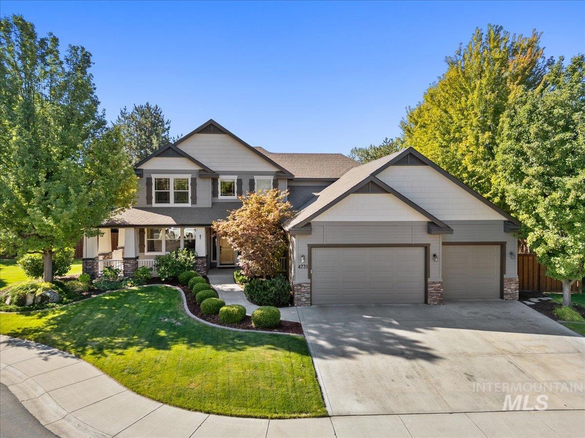 Craftsman-style house with stone siding, covered porch, concrete driveway, and a garage