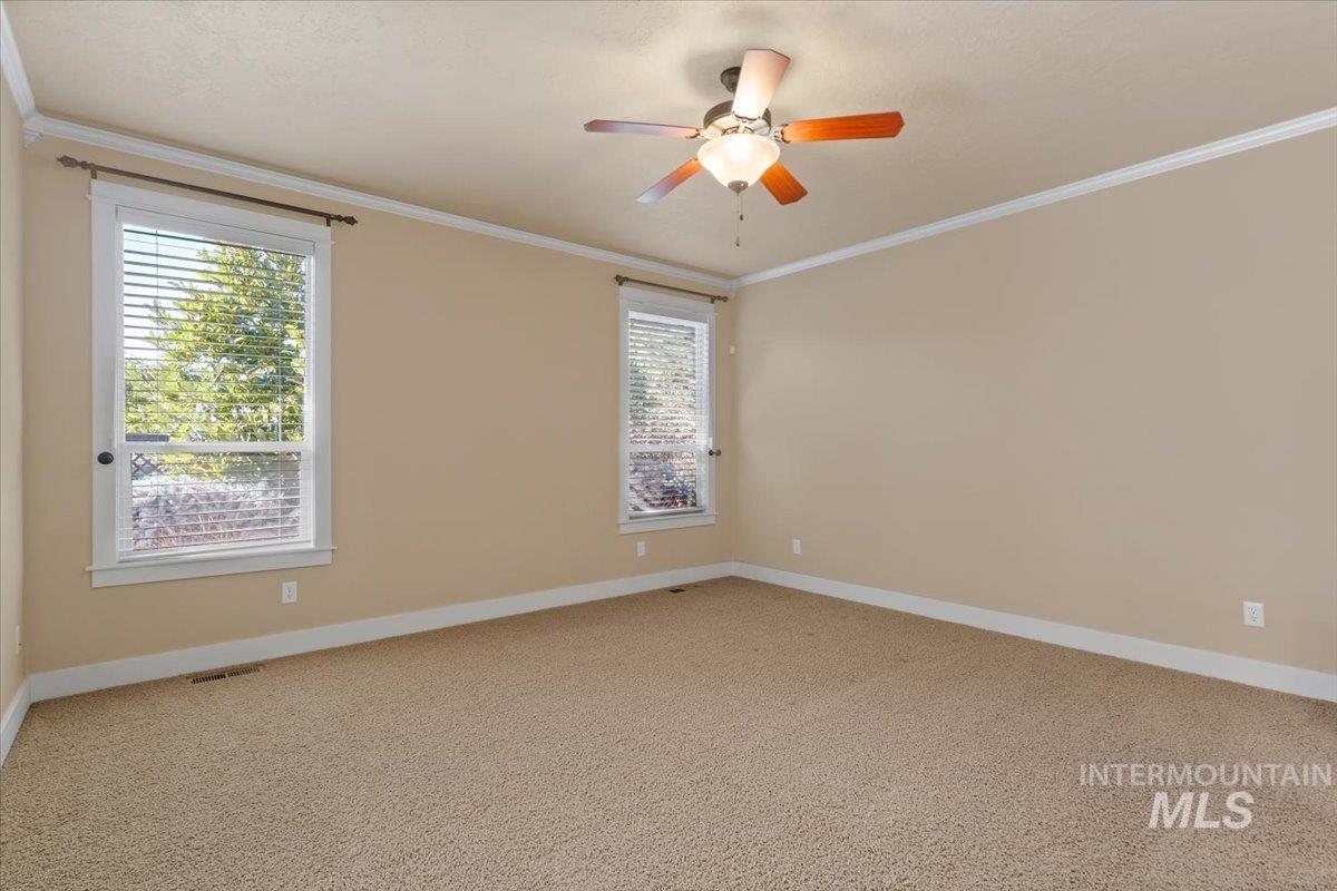 Unfurnished room featuring ornamental molding, light carpet, and a ceiling fan
