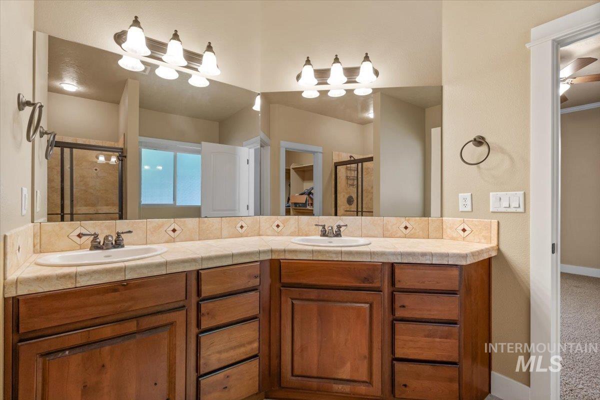 Bathroom with a shower stall, double vanity, and a textured wall