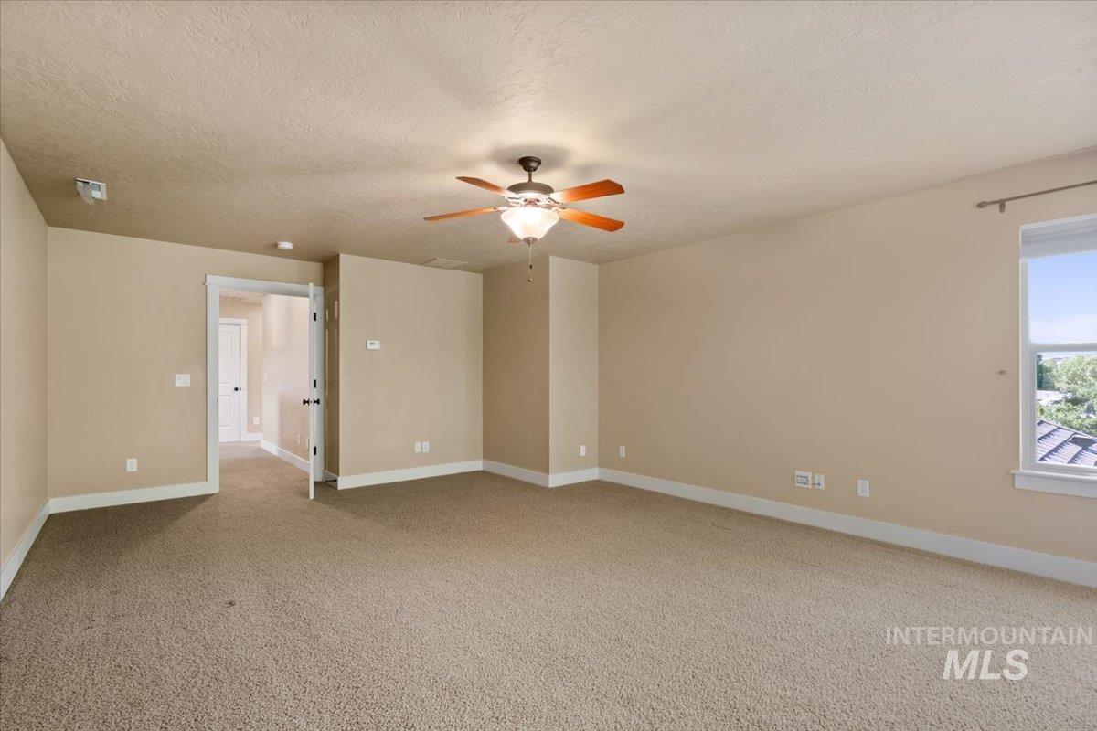 Unfurnished room with light colored carpet, a textured ceiling, and ceiling fan