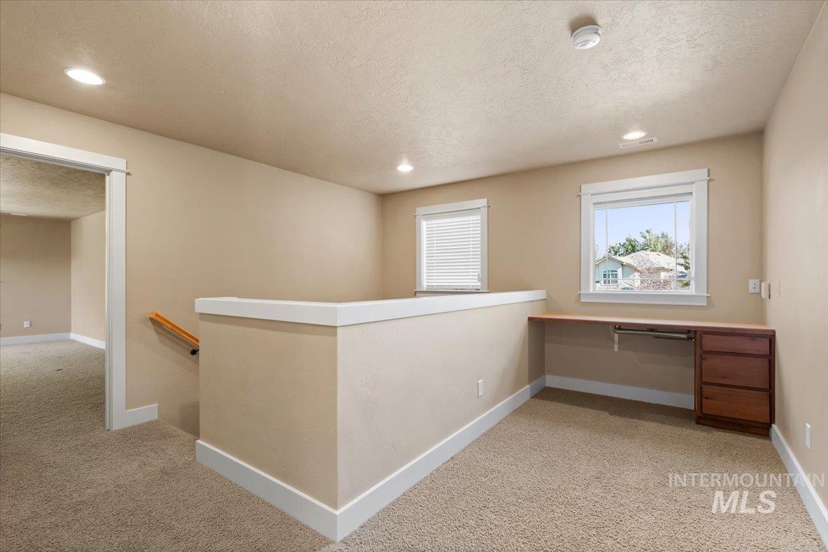 Hall featuring light carpet, a textured ceiling, an upstairs landing, recessed lighting, and an office area