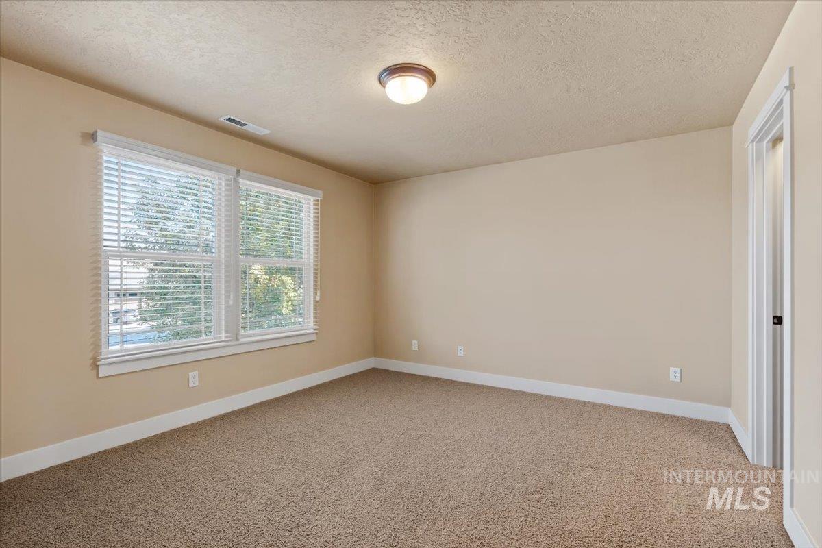 Unfurnished room with light colored carpet and a textured ceiling