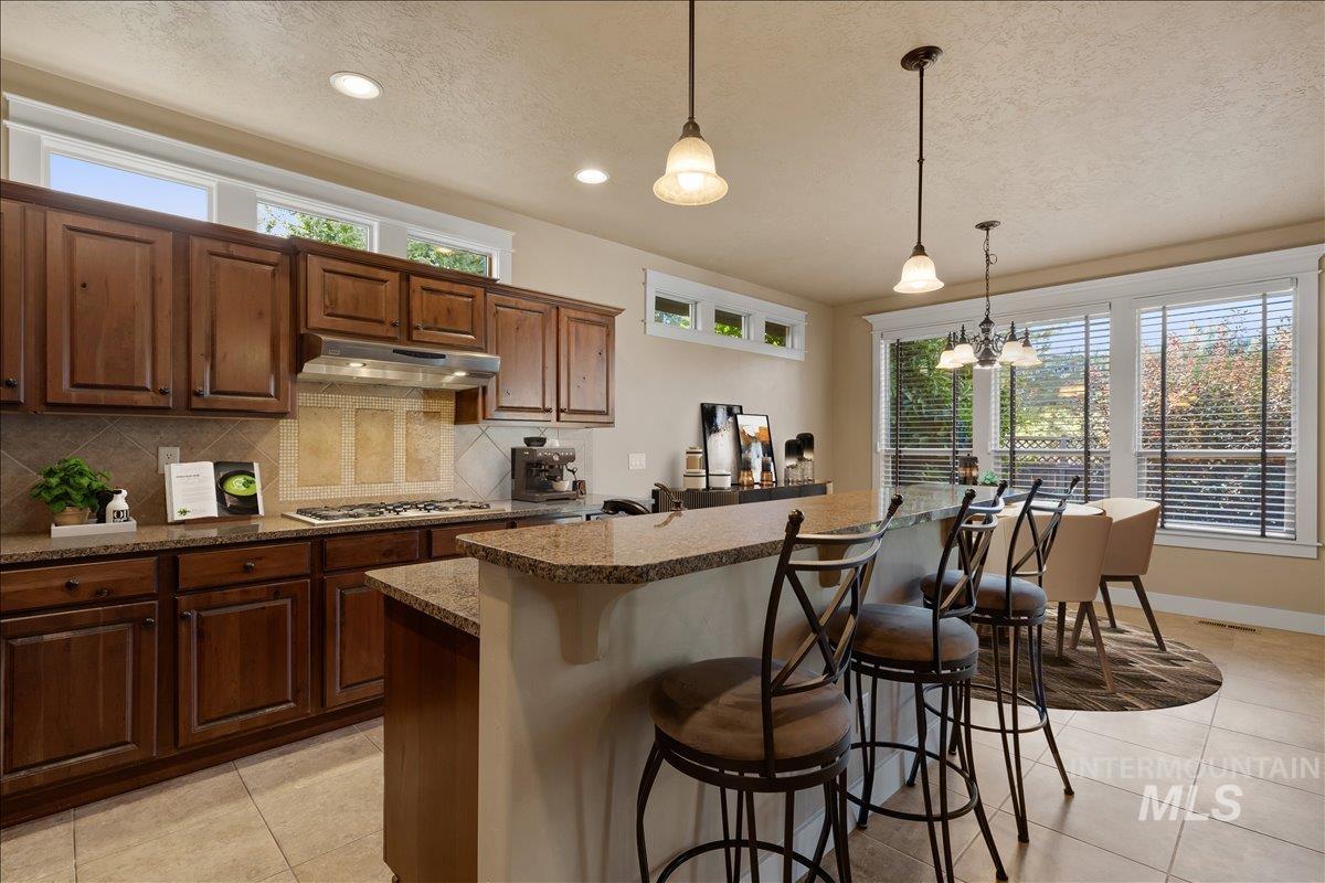 Kitchen featuring a breakfast bar area, healthy amount of natural light, backsplash, pendant lighting, and a textured ceiling