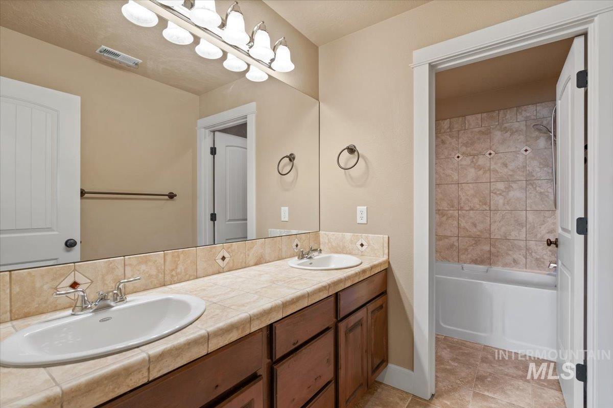 Full bathroom with  shower combination, double vanity, and light tile patterned flooring