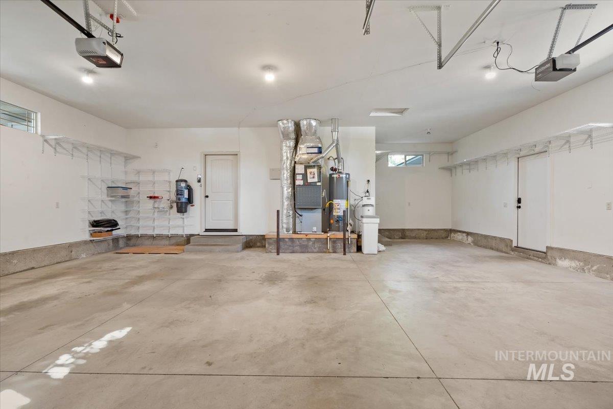 Garage featuring gas water heater, a garage door opener, and heating unit