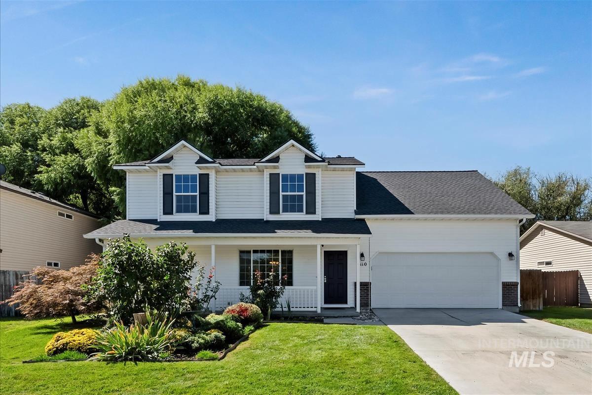 Traditional-style home with a porch, driveway, an attached garage, and a shingled roof