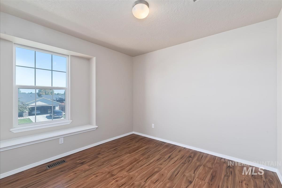 Empty room featuring wood finished floors and a textured ceiling