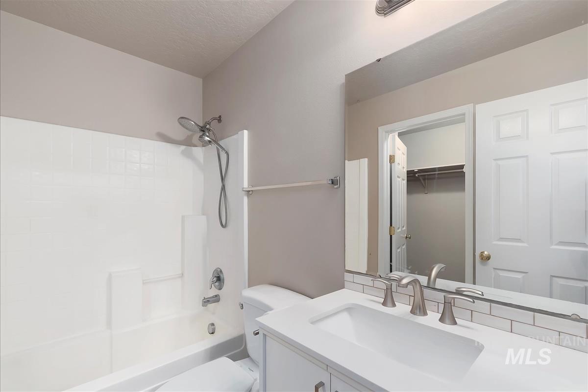 Bathroom with vanity, tub / shower combination, and a textured ceiling