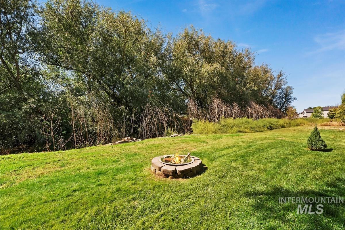 View of green lawn featuring an outdoor fire pit