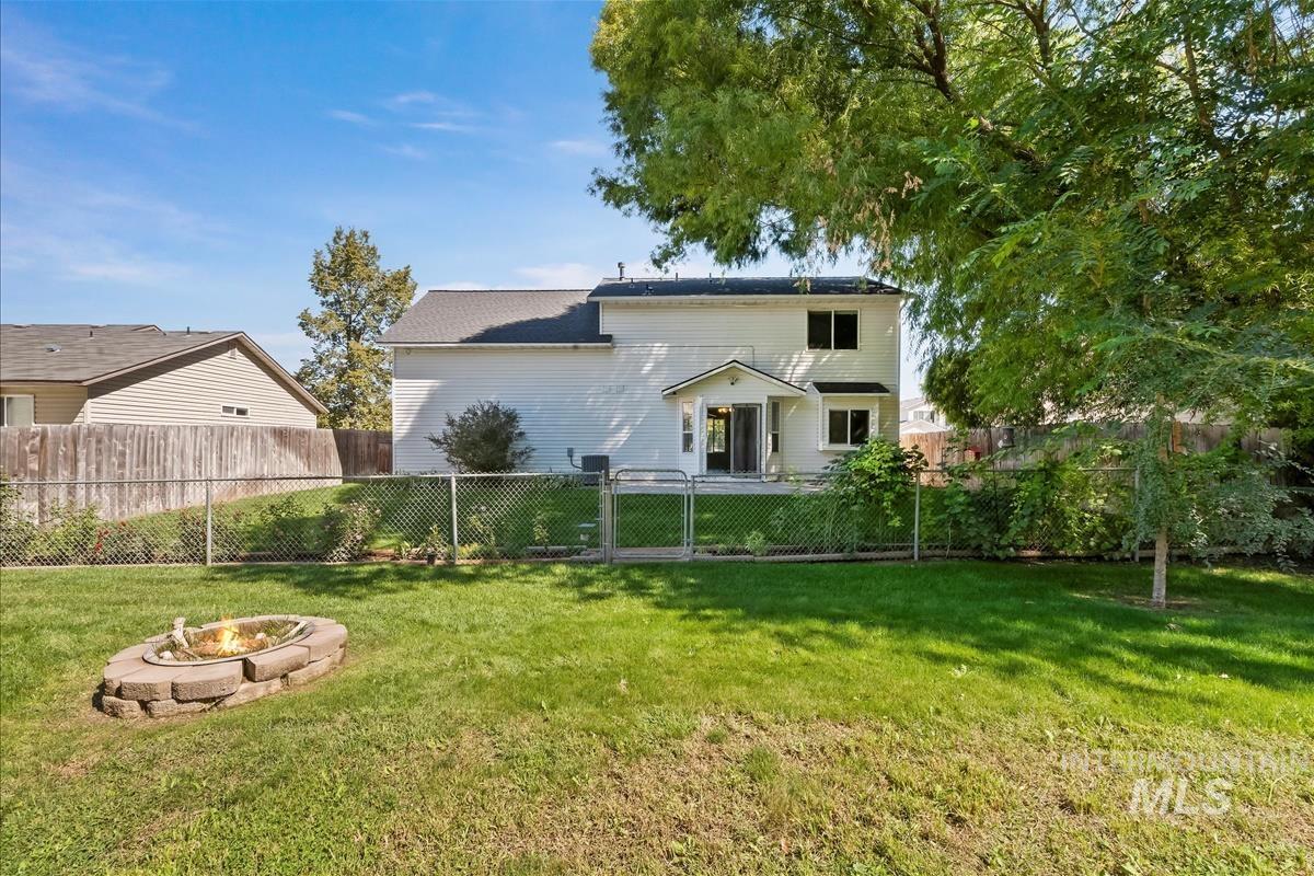 Rear view of house with a fenced backyard, a fire pit, and a gate