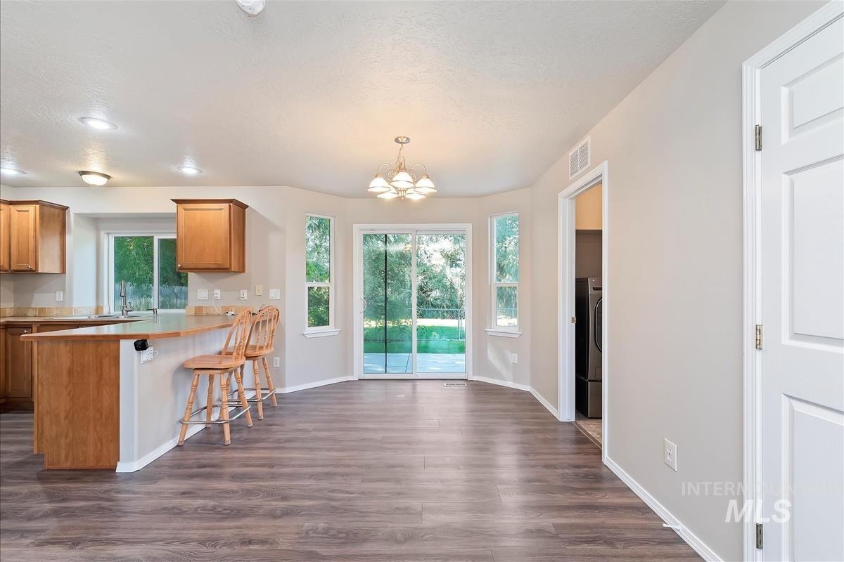Kitchen featuring light countertops, a breakfast bar area, dark wood finished floors, a chandelier, and brown cabinetry