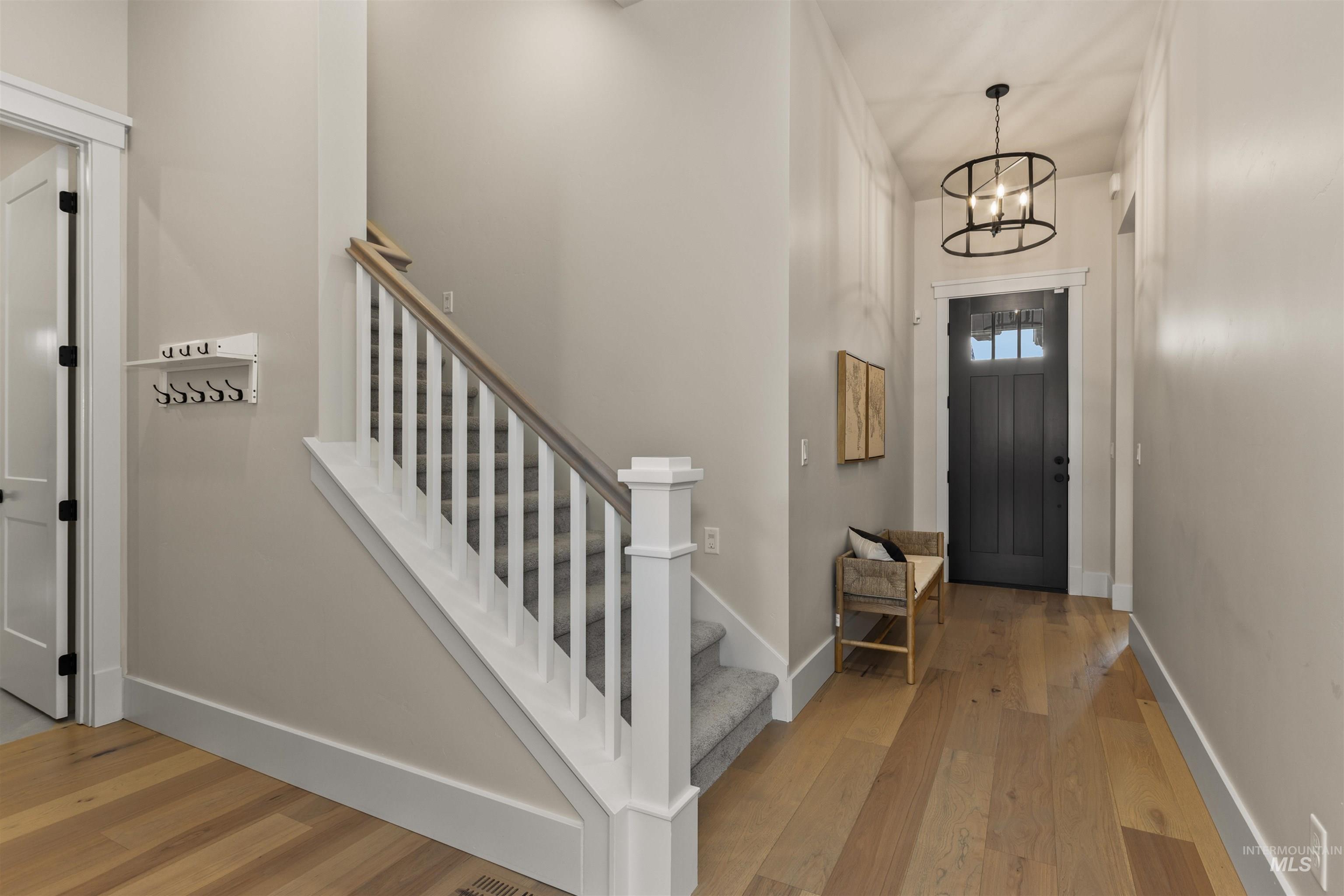 Foyer featuring light wood-type flooring, a chandelier, and stairs