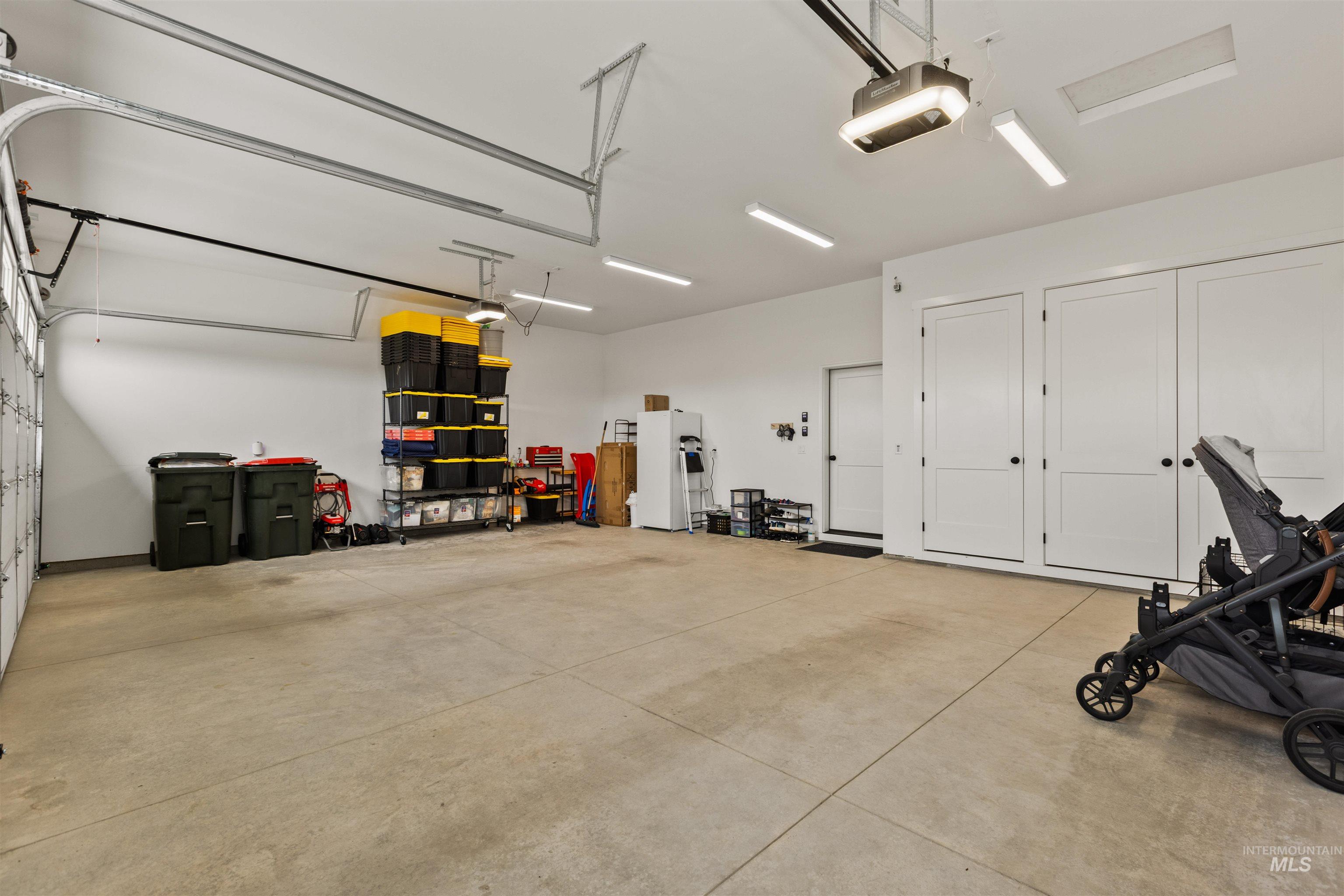 Garage with a garage door opener and freestanding refrigerator