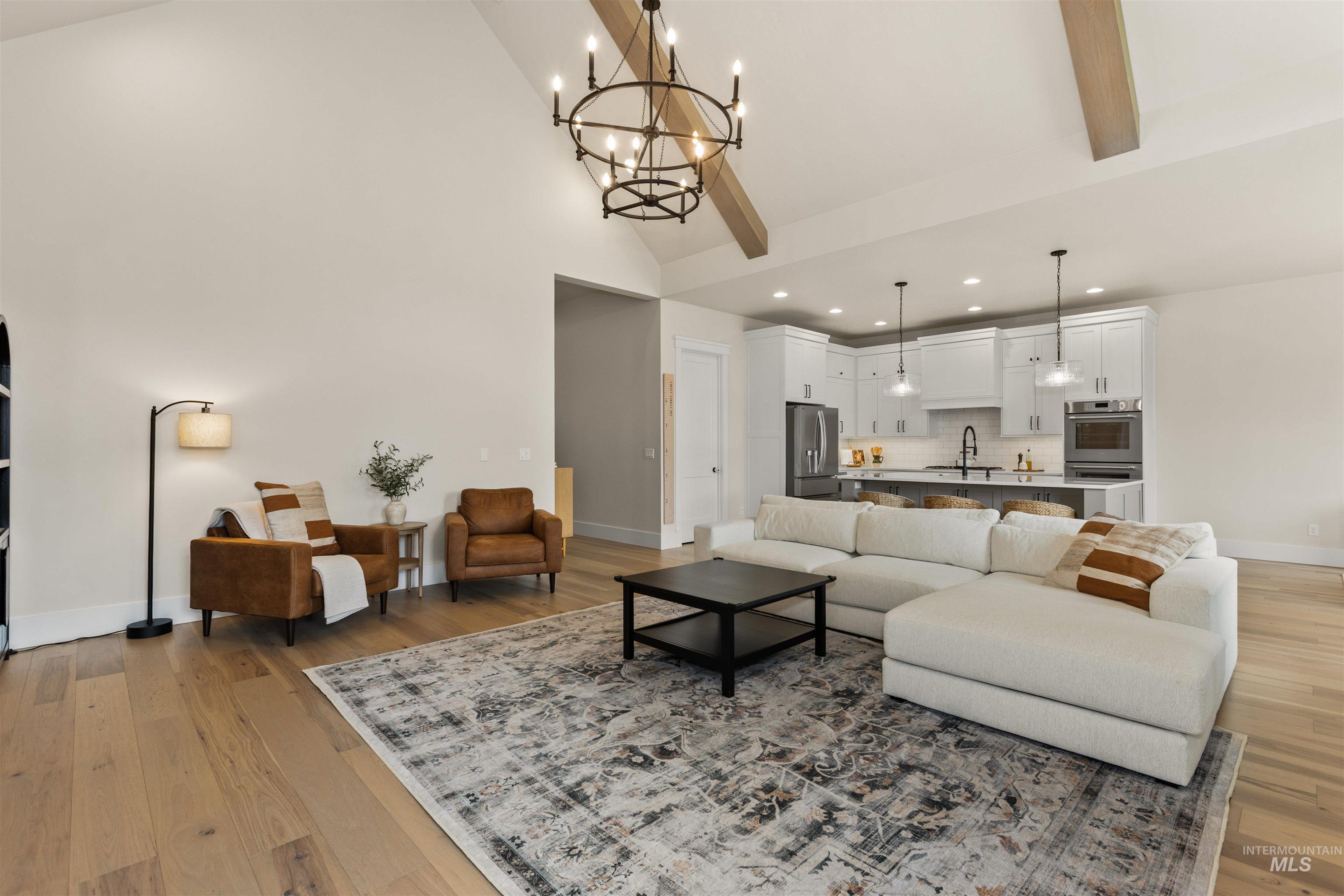 Living area with light wood-style floors, recessed lighting, high vaulted ceiling, a chandelier, and beam ceiling