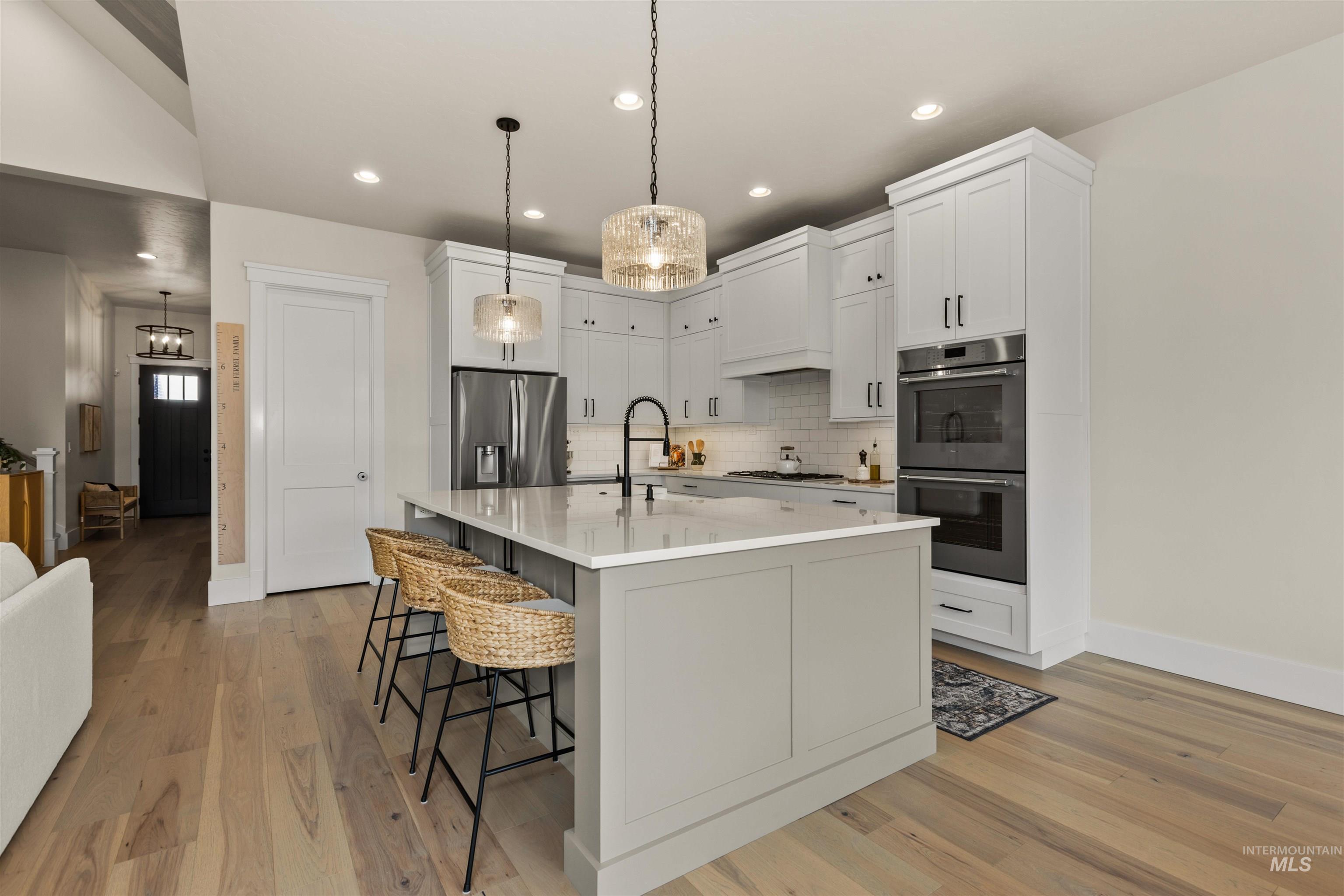 Kitchen with appliances with stainless steel finishes, backsplash, a breakfast bar area, light wood-style floors, and recessed lighting