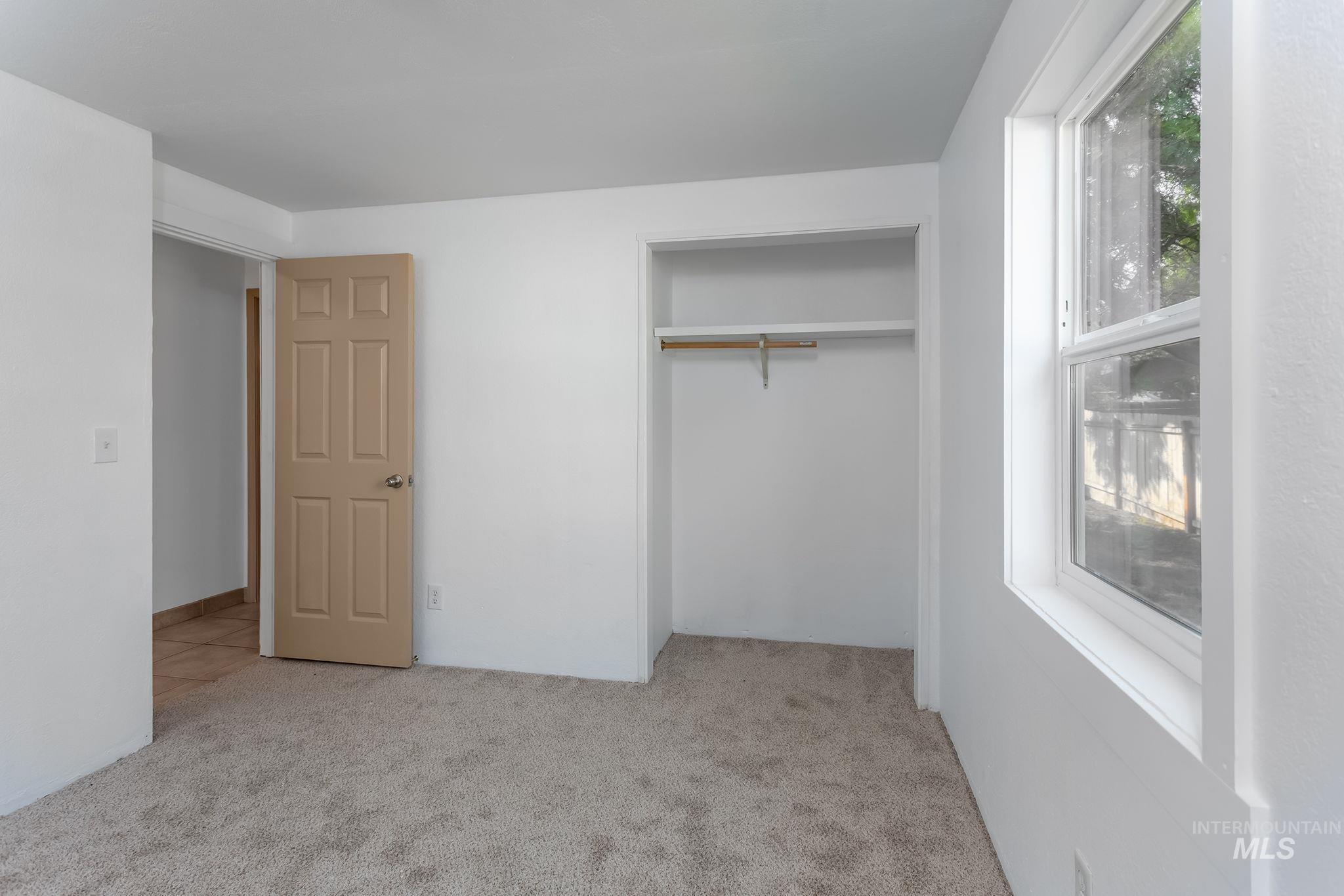 Unfurnished bedroom featuring light carpet and a closet