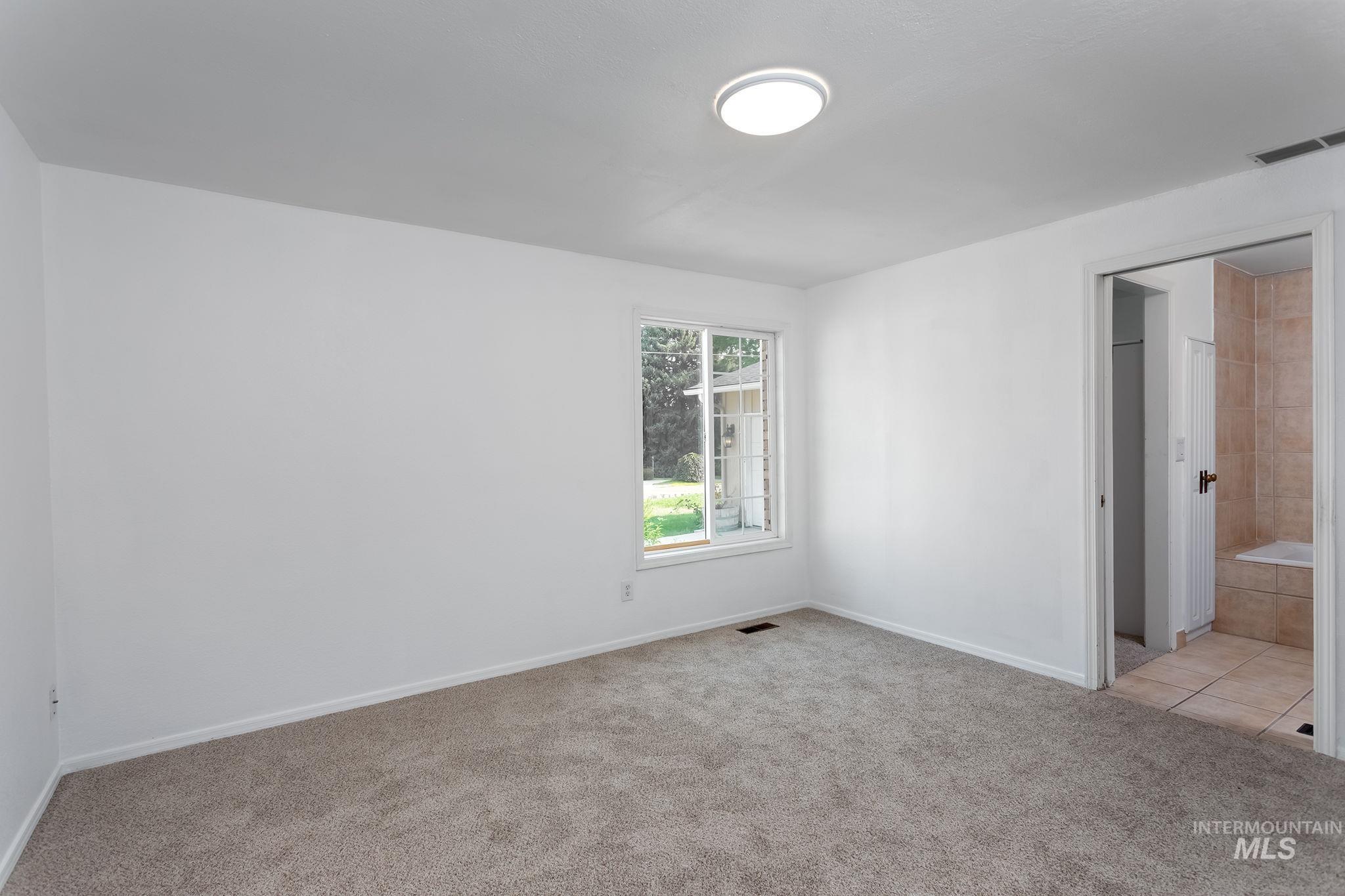 Unfurnished bedroom with light colored carpet and ensuite bath