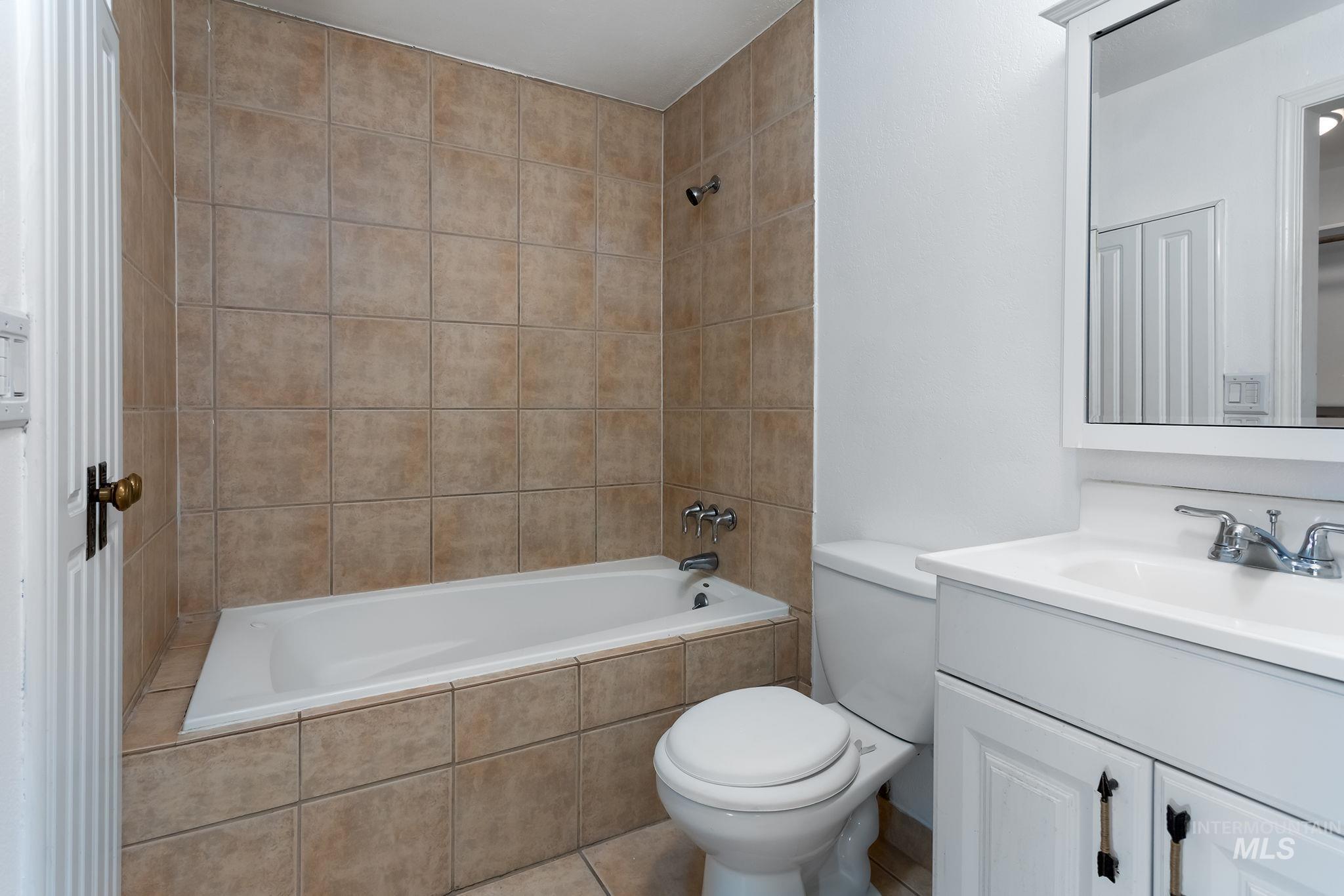 Bathroom featuring tiled shower / bath combo, vanity, and tile patterned floors