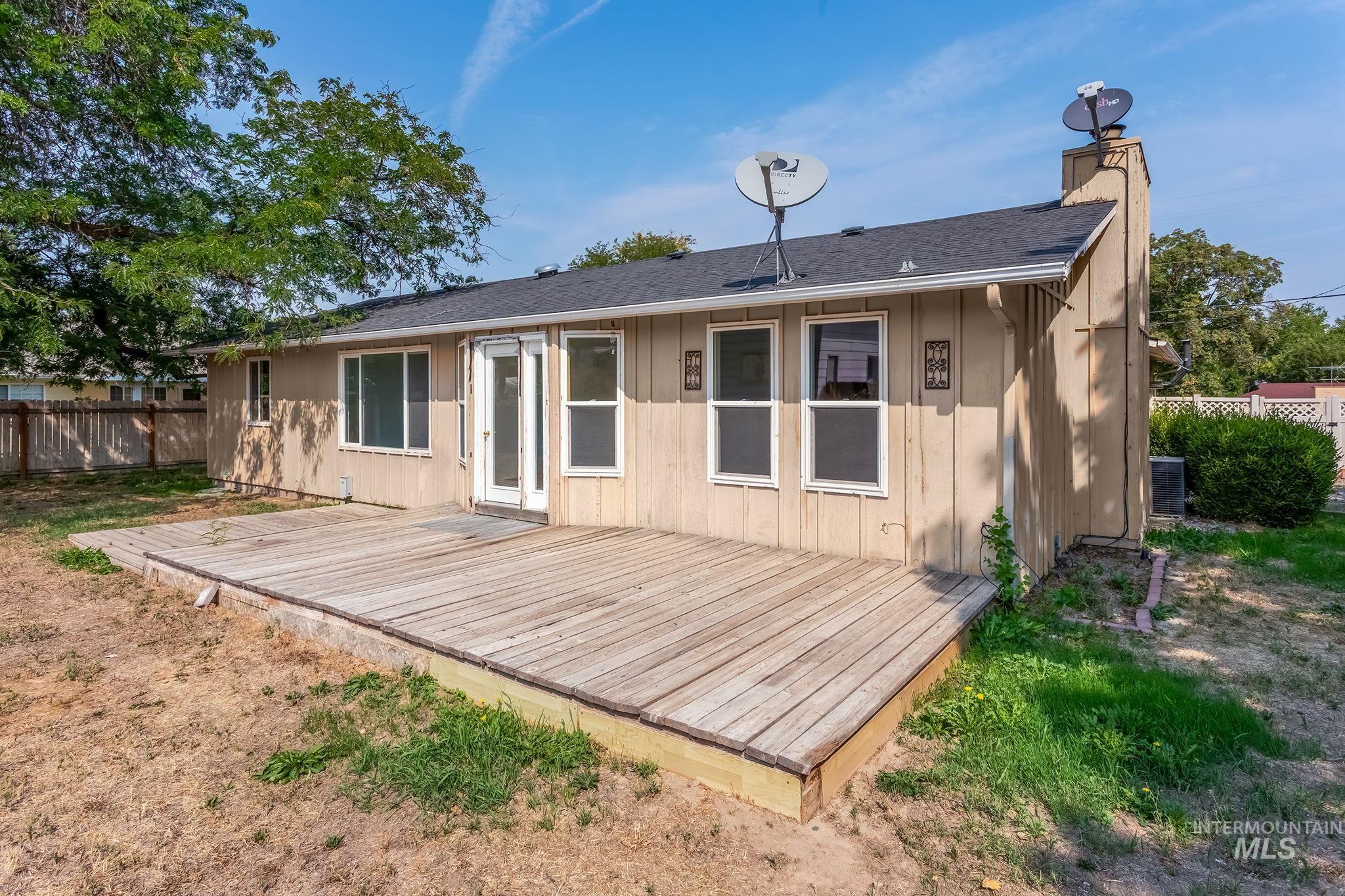 Back of property featuring a wooden deck, a chimney, and a shingled roof