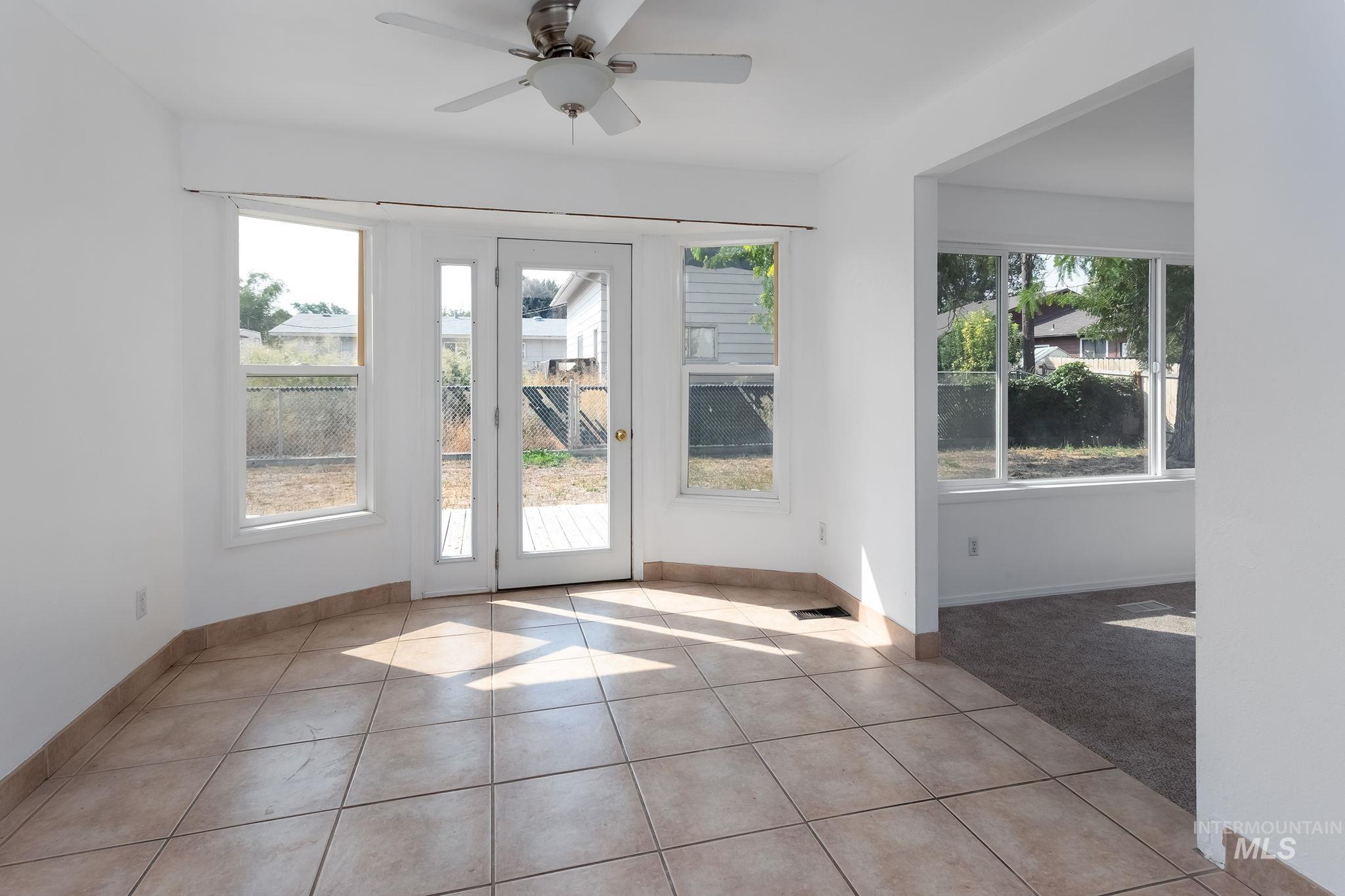 Doorway with tile patterned floors, plenty of natural light, and ceiling fan